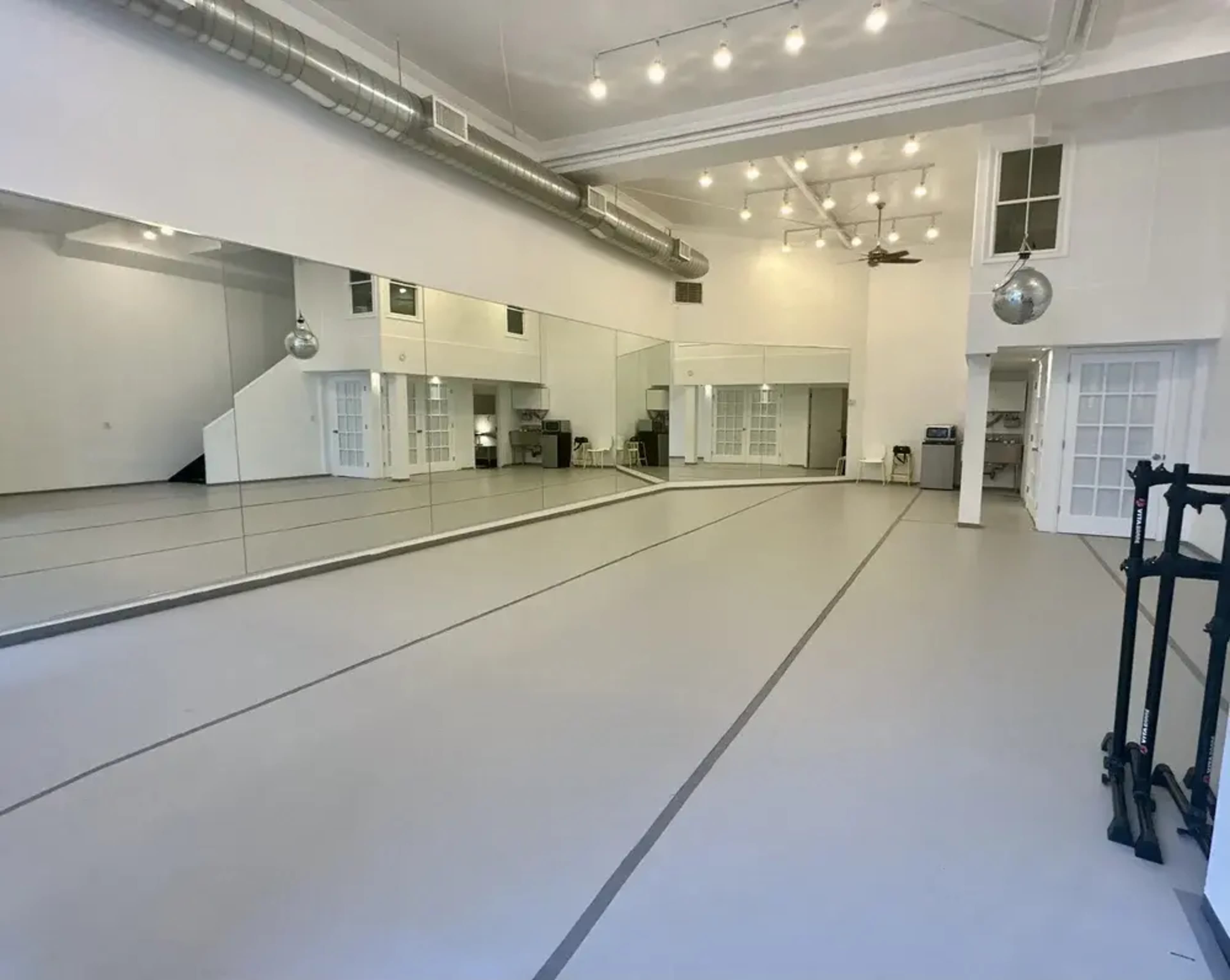 The image shows a spacious, well-lit studio with large mirrors along one wall and a smooth floor surface.