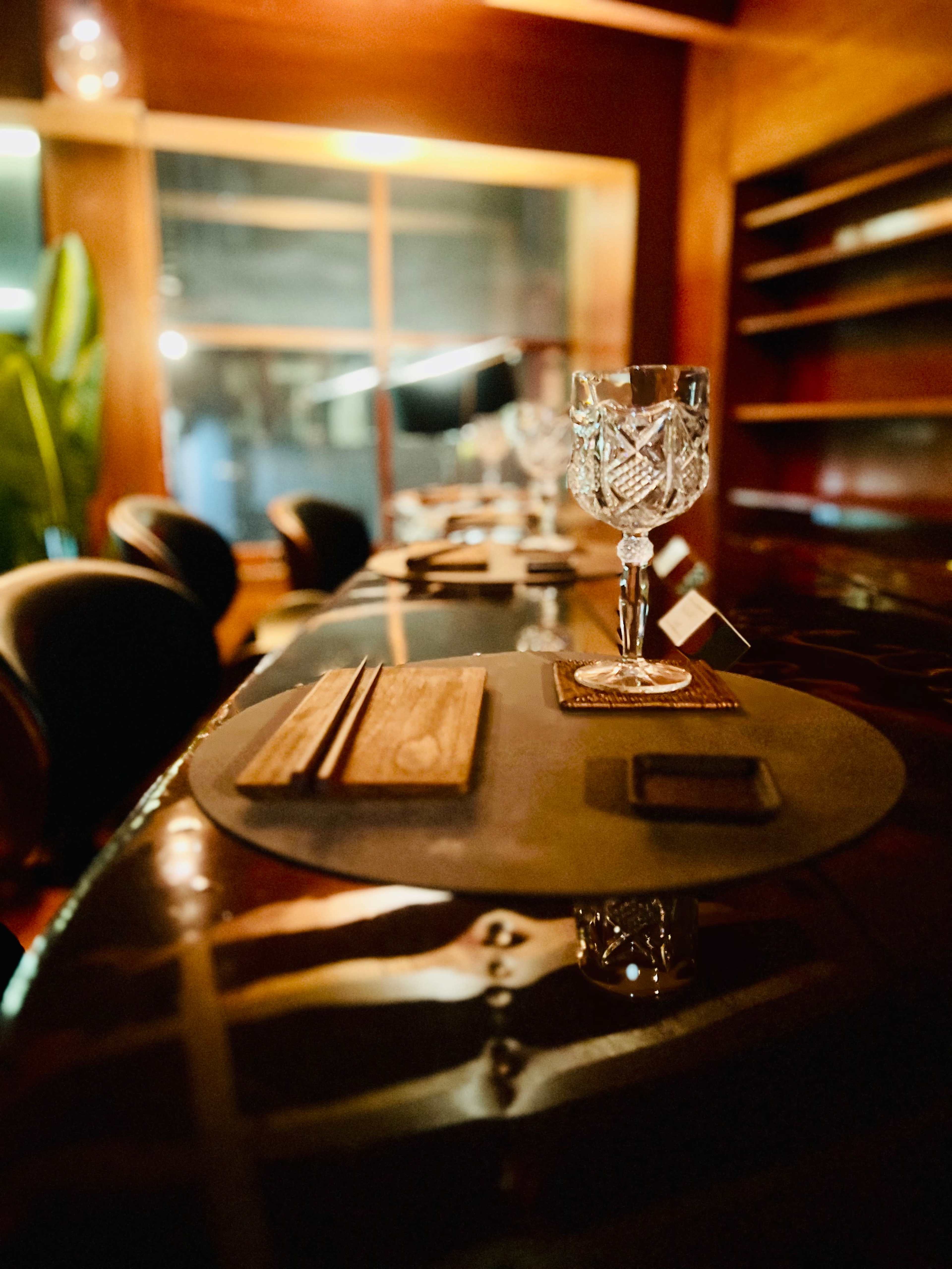 A dimly lit bar counter with a decorative glass and wooden coasters arranged on it.
