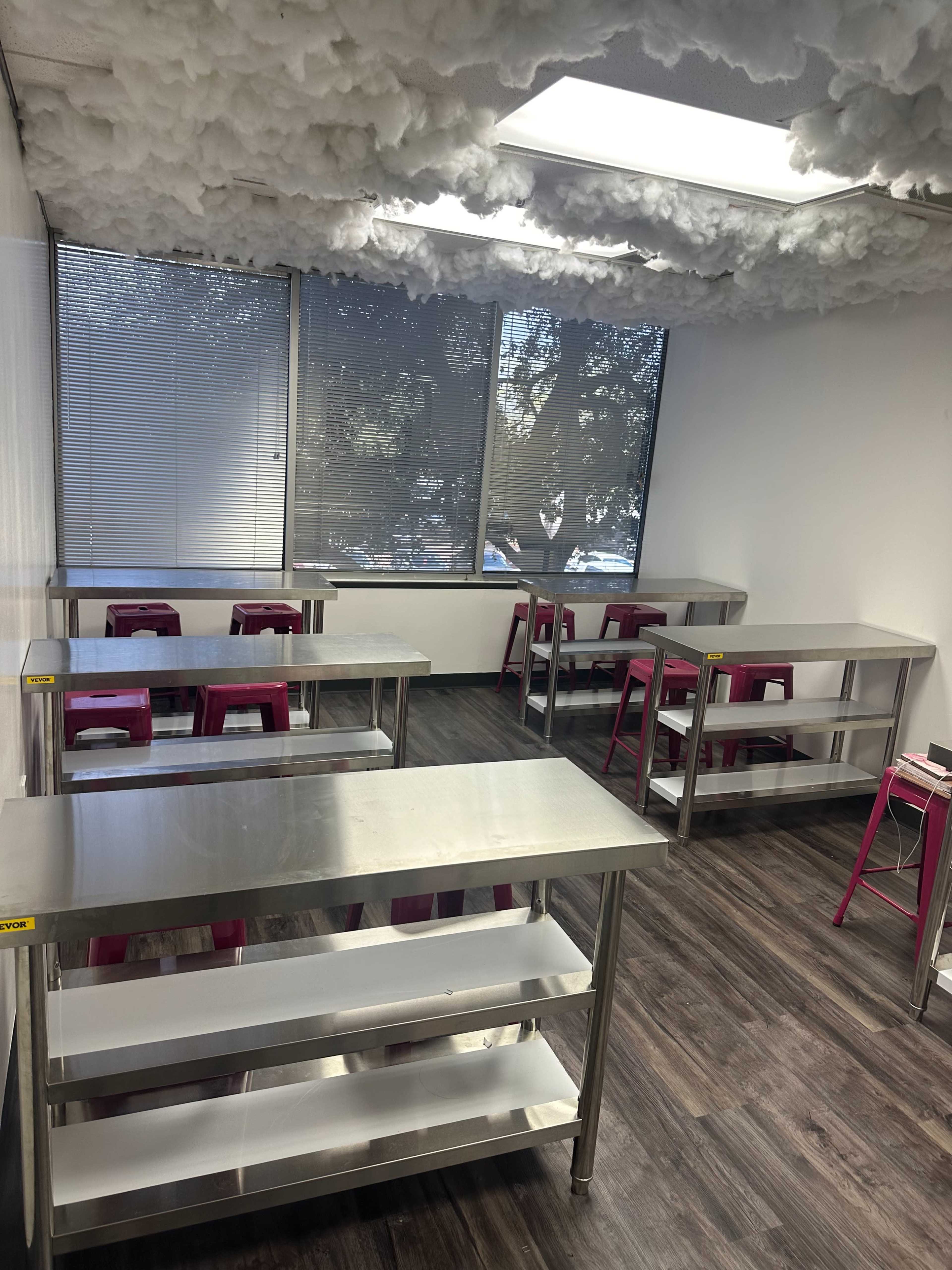 A classroom with stainless steel tables and chairs, along with a ceiling covered in a fluffy material.
