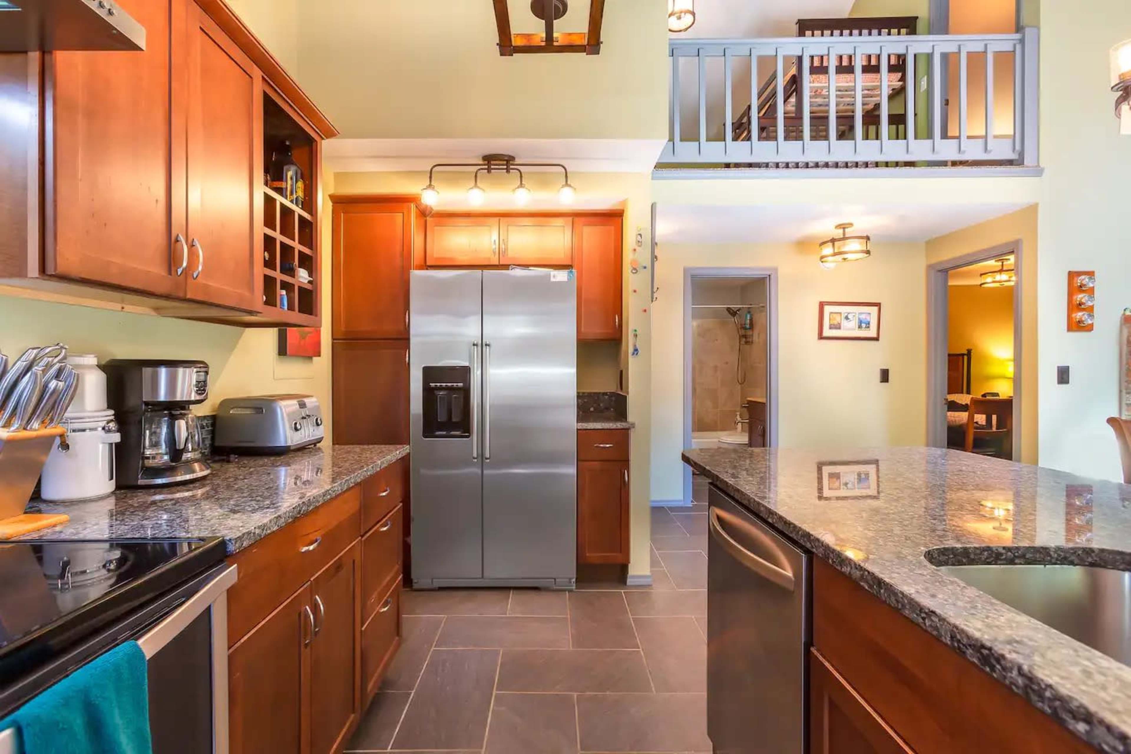 A modern kitchen with dark wood cabinetry, stainless steel appliances, and a granite countertop.