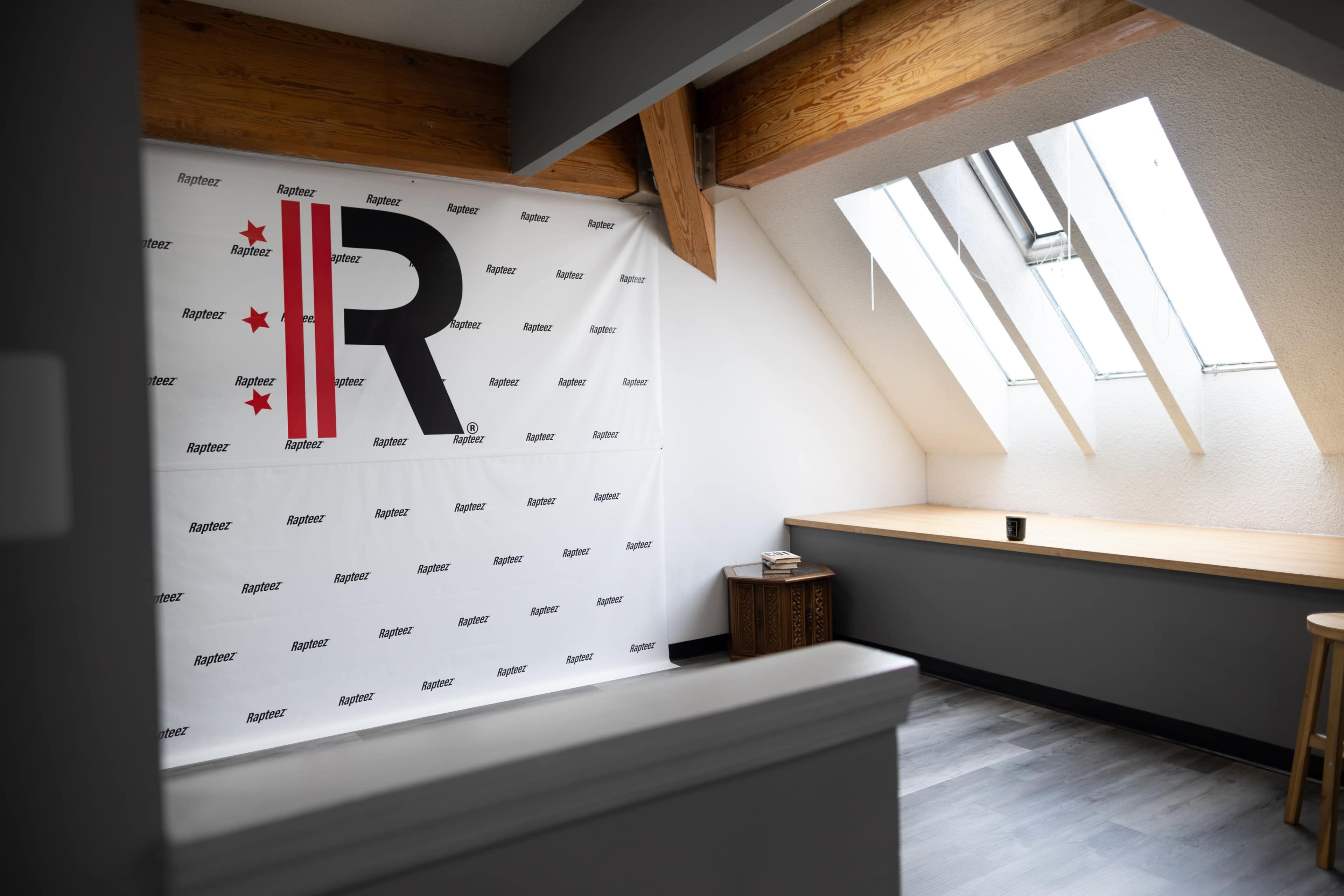 The image shows a room with a sloped ceiling featuring a large backdrop with the letter "R" and stars, and a narrow wooden shelf along the wall.