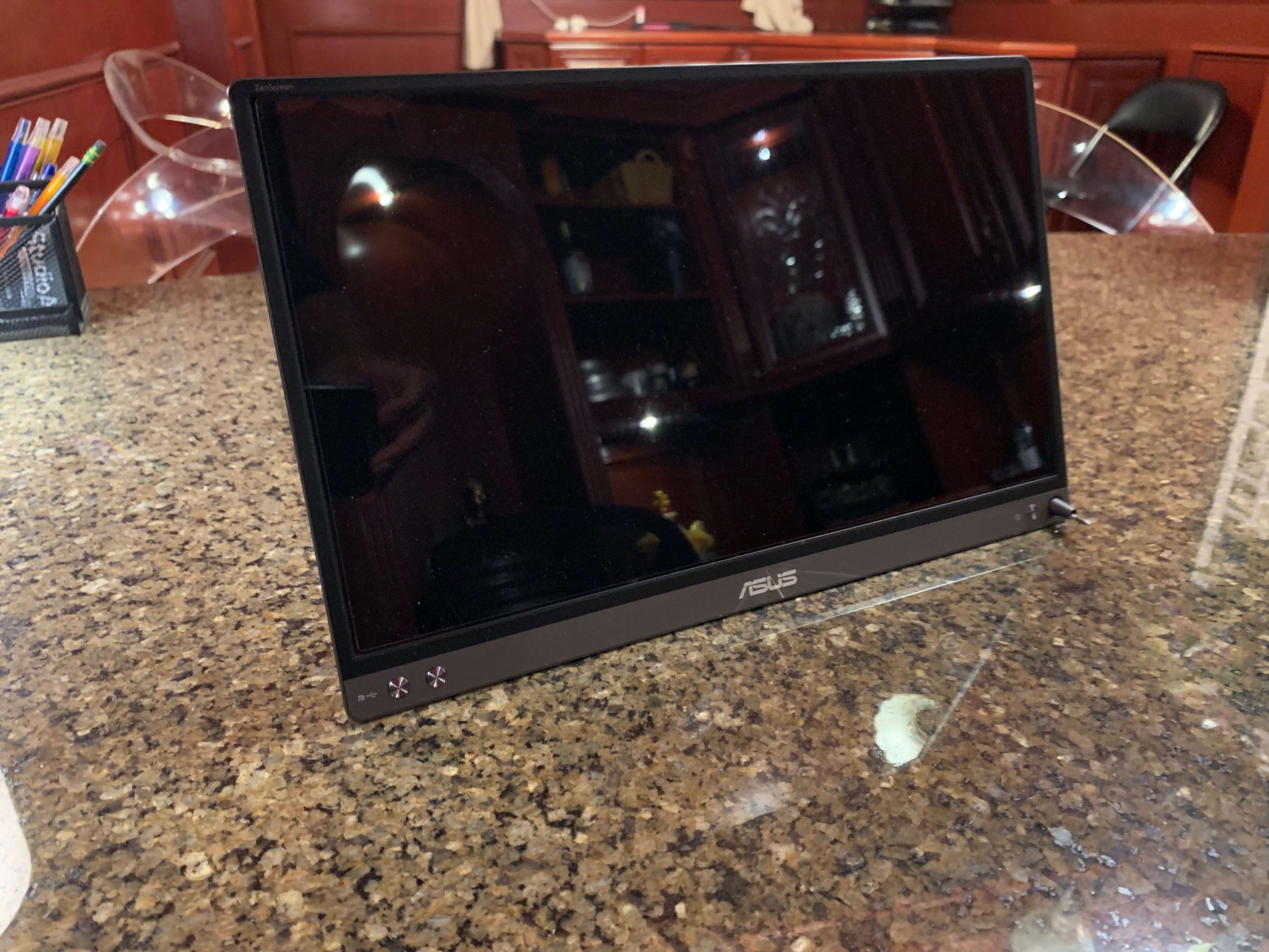 A sleek, black Asus portable monitor is displayed on a granite countertop.
