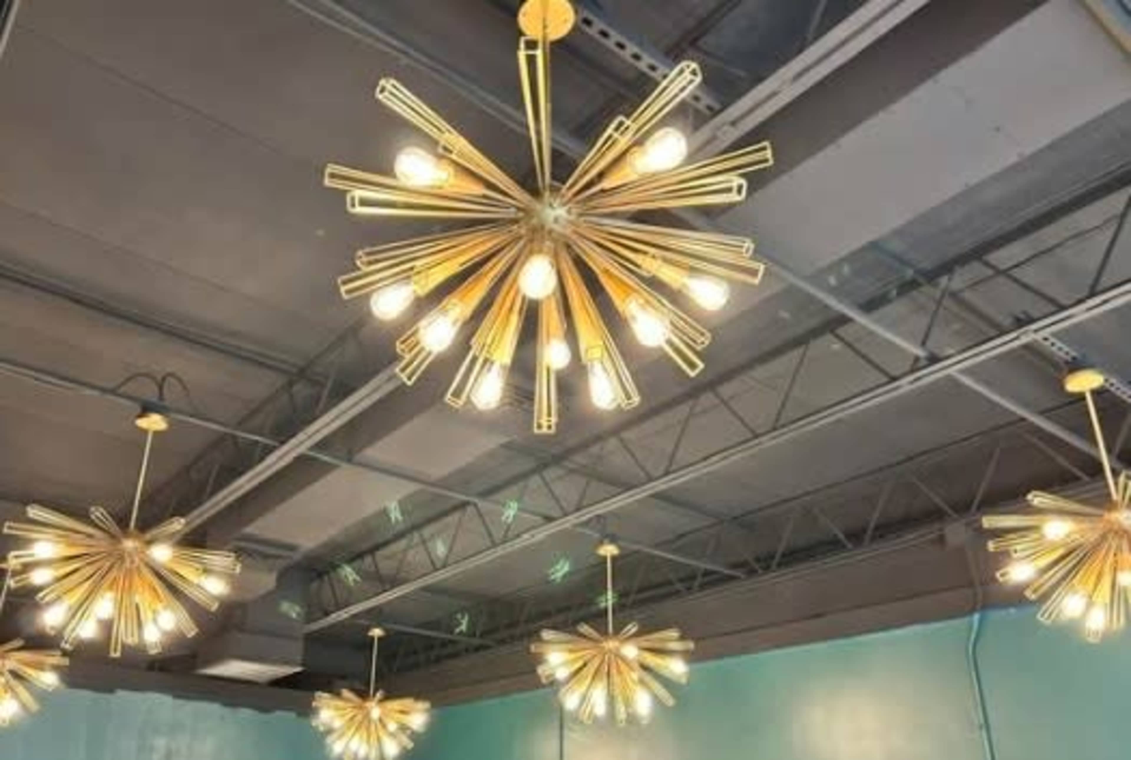 The image features multiple starburst-style light fixtures hanging from a ceiling in a room with a teal wall.