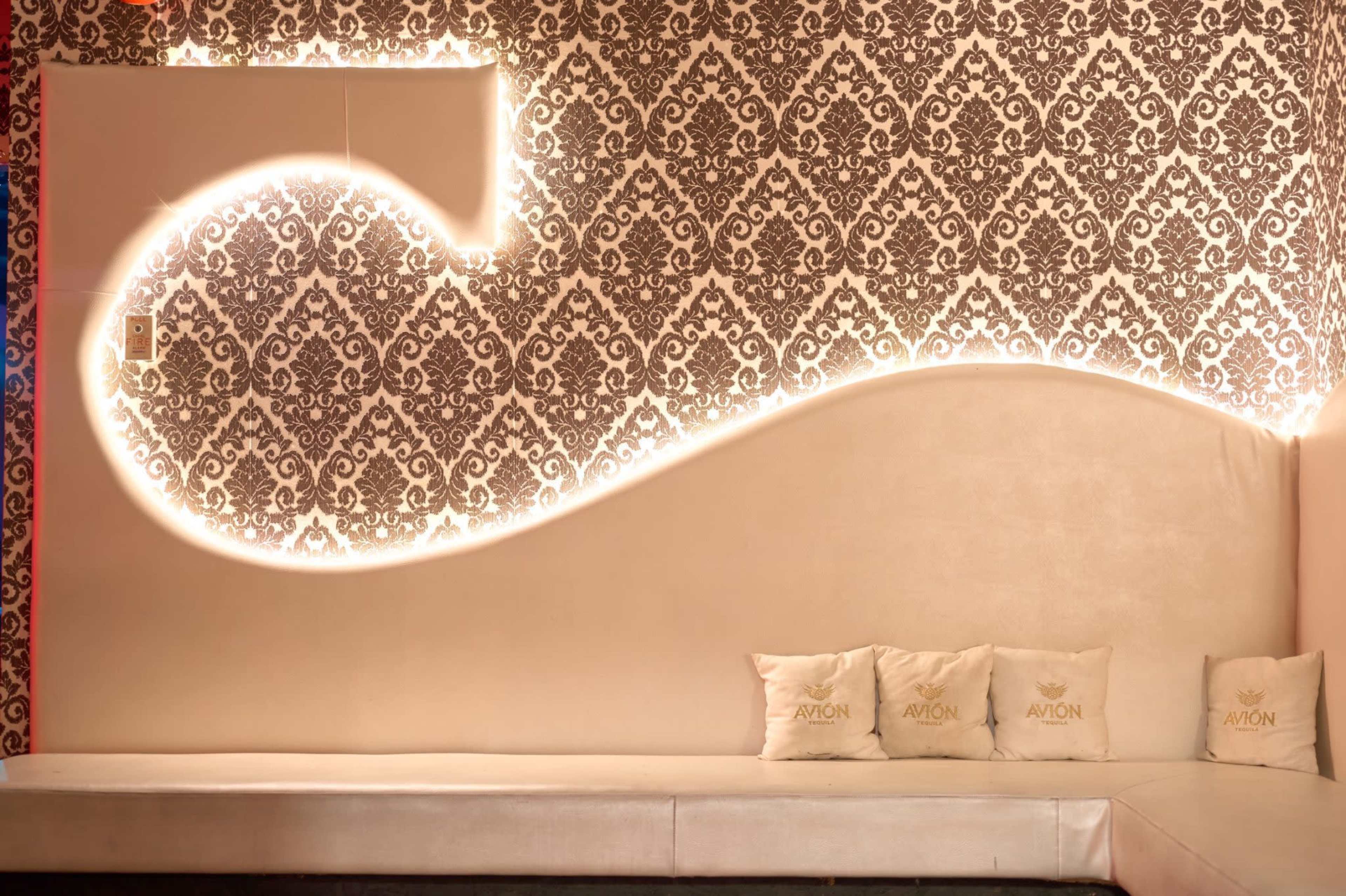 A modern seating area with a white sofa against a decorative wall featuring an intricate pattern and softly illuminated accents.