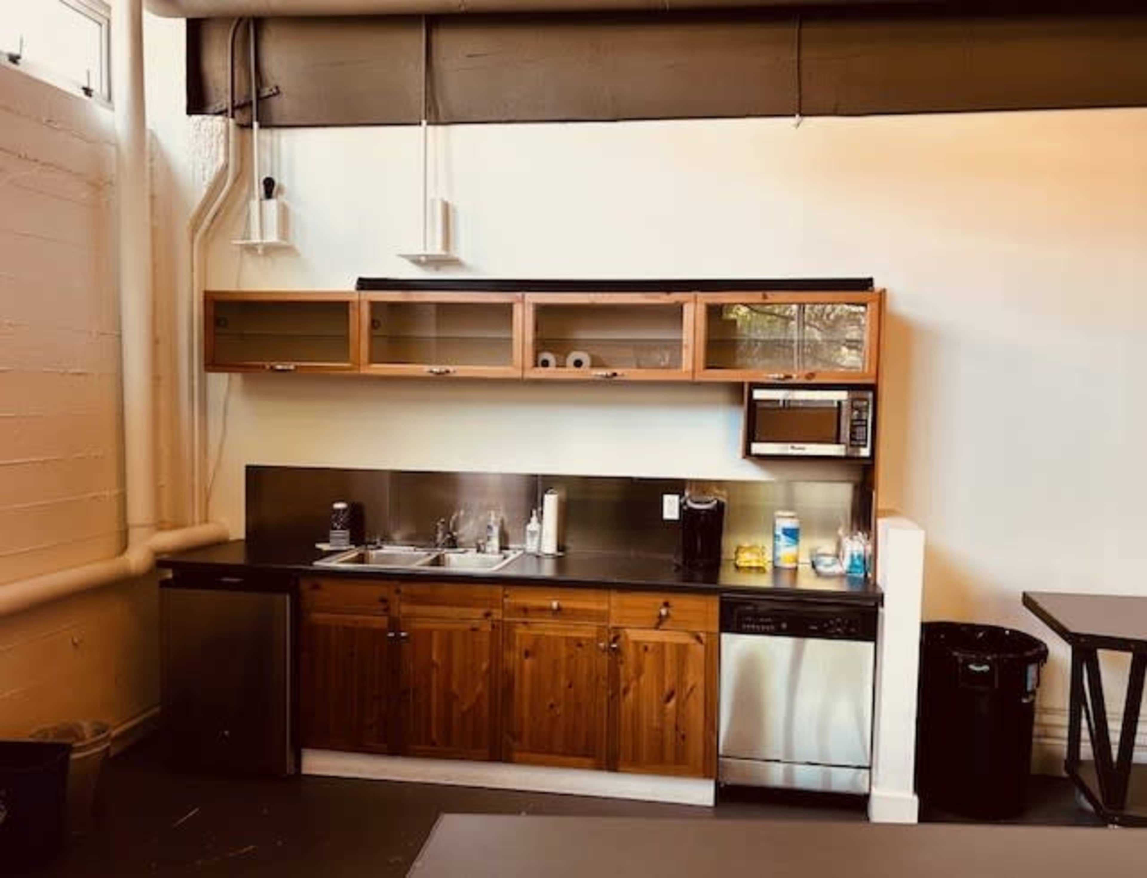A modern kitchen area featuring wooden cabinetry, stainless steel appliances, a sink, and a countertop with various kitchen items.