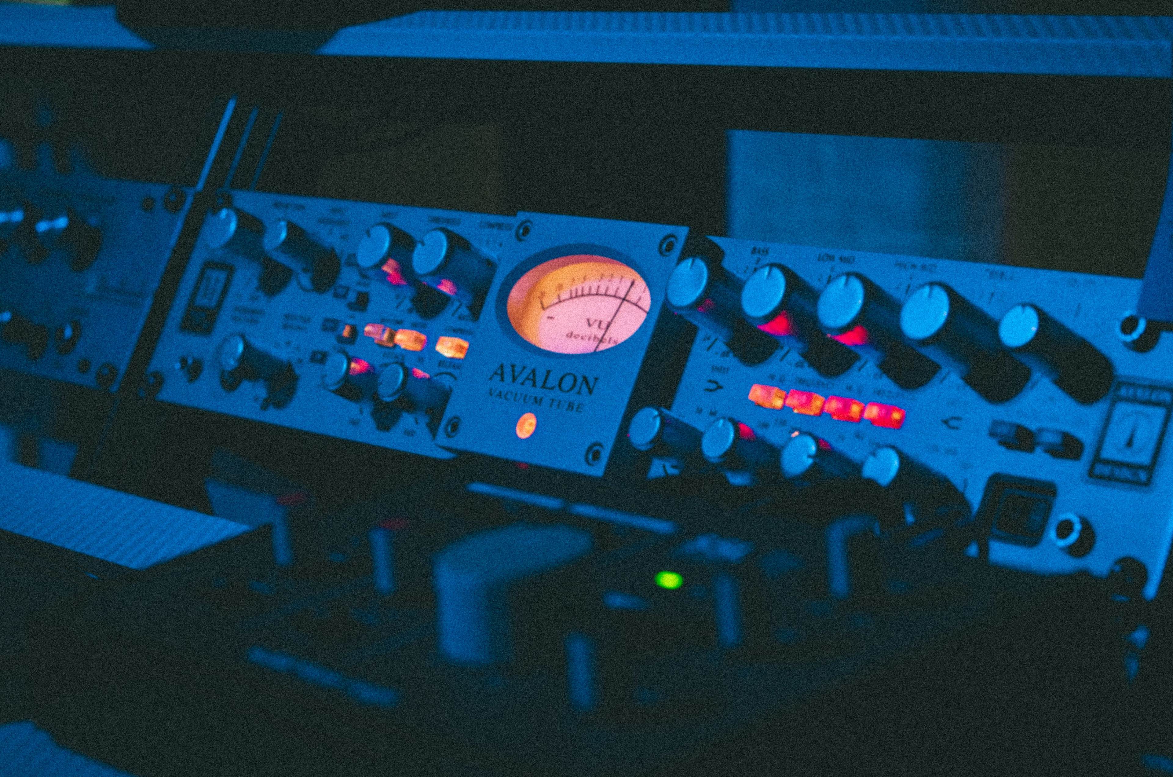 The image shows a close-up of an Avalon audio device with illuminated dials and meters.
