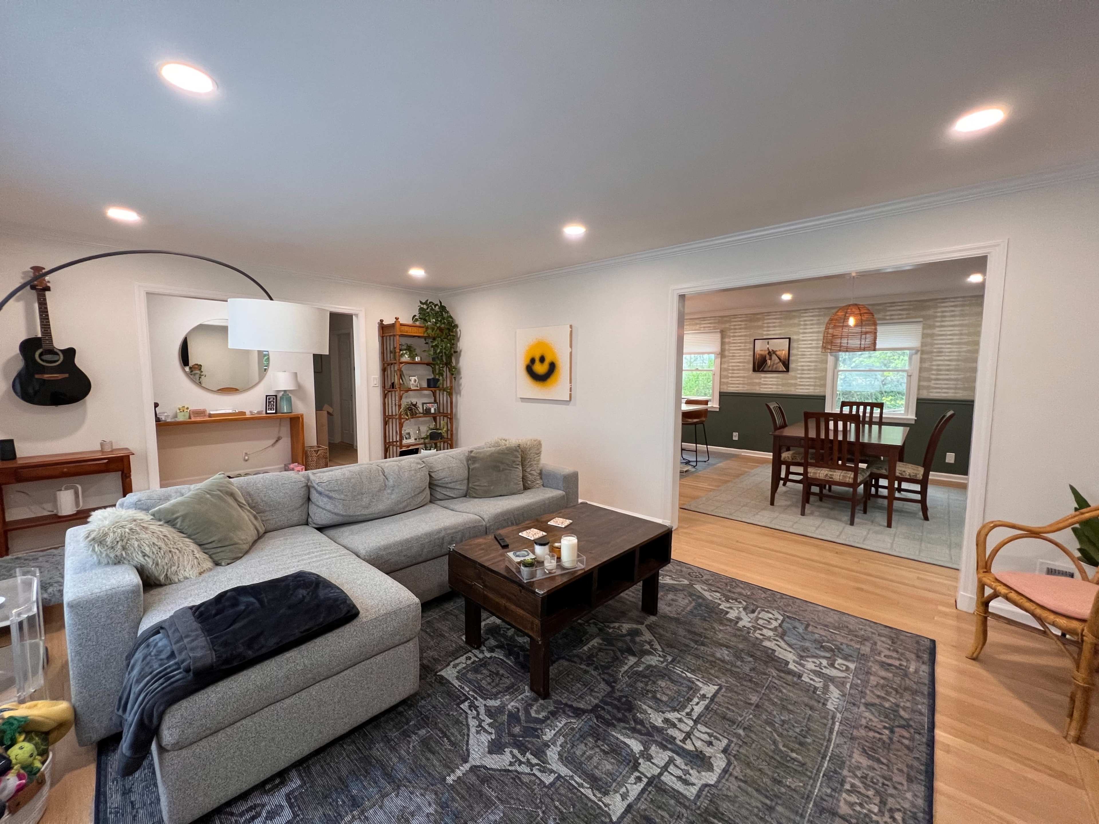 A cozy living room with a gray sectional sofa, a coffee table in front, and an adjacent dining area visible through an open doorway.