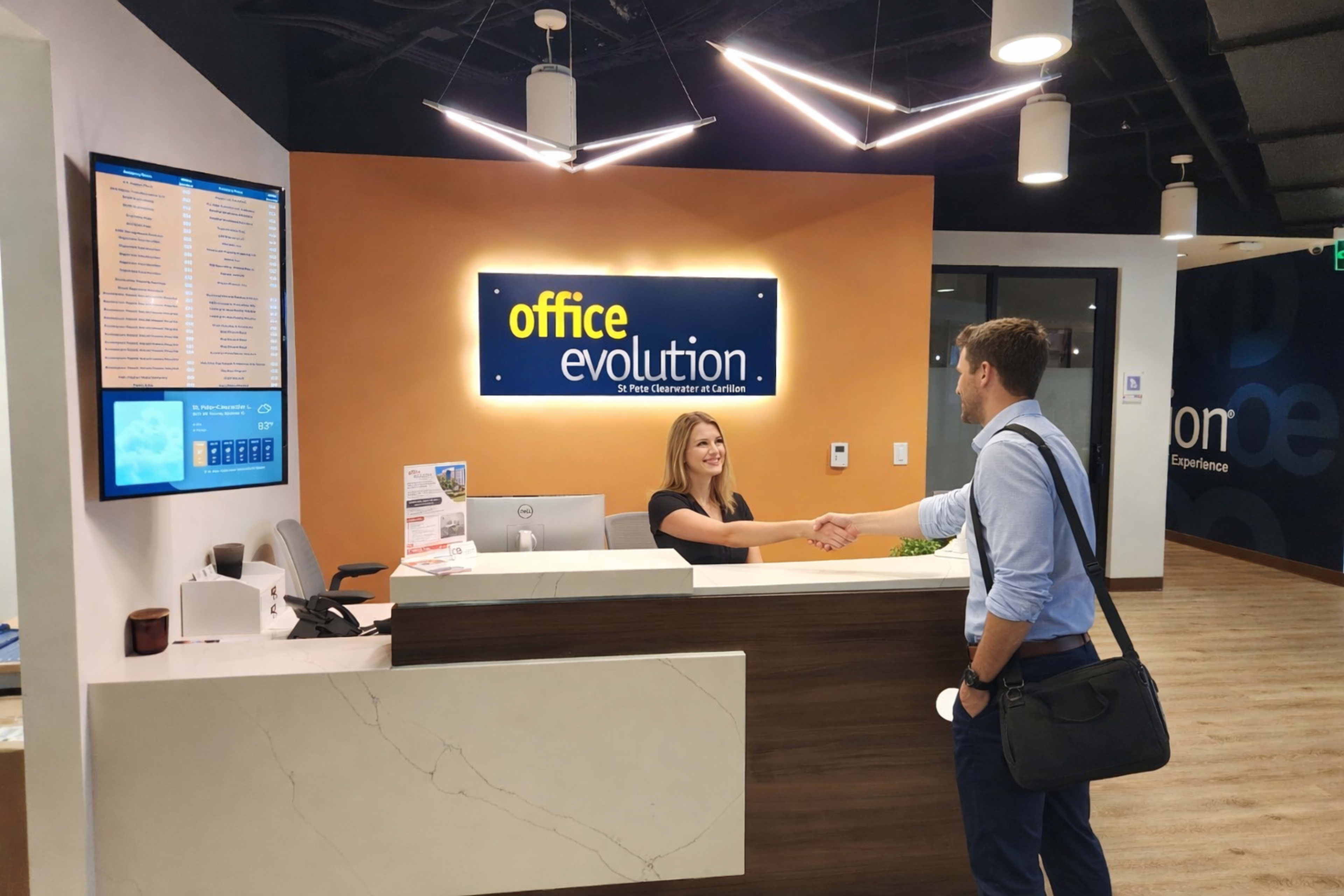 A person is shaking hands with a receptionist at a modern office reception area featuring a sign that reads "office evolution."