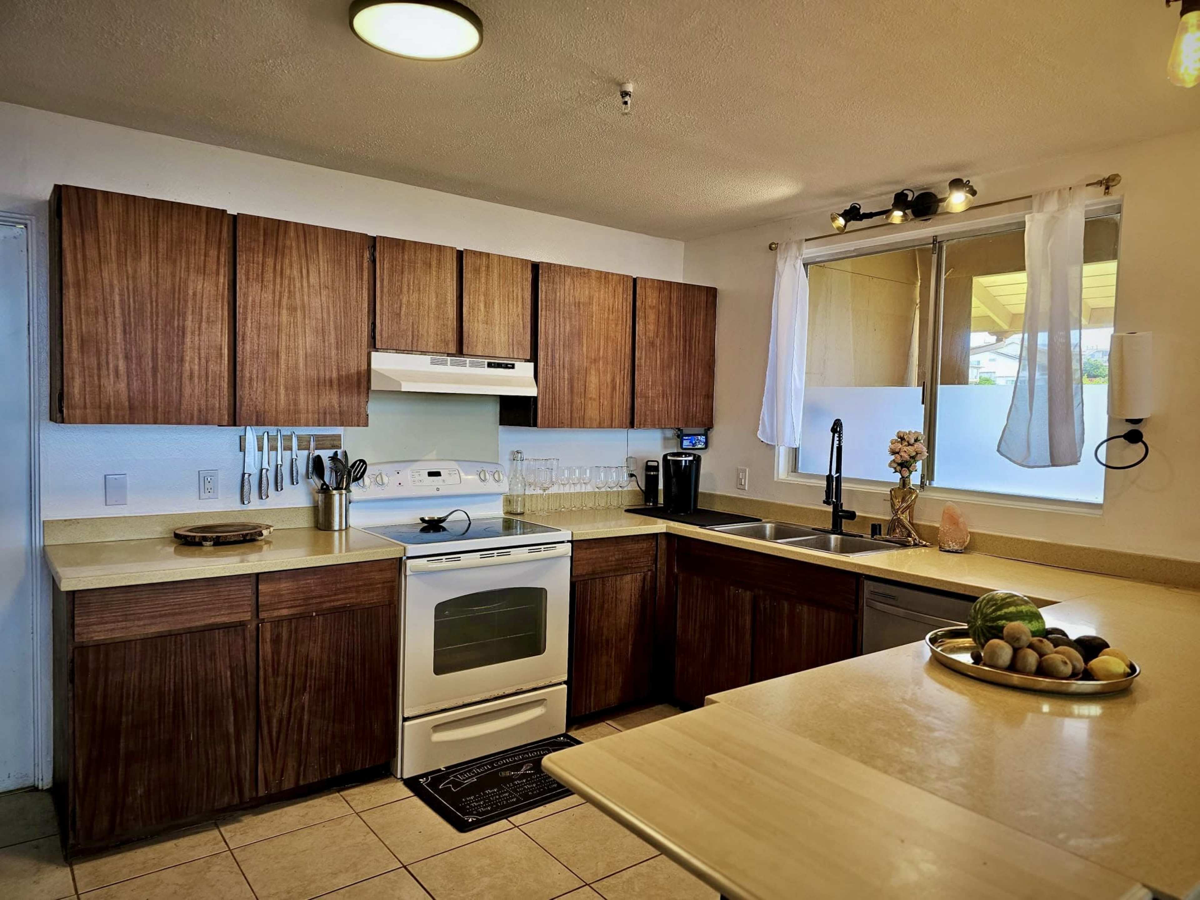A kitchen with wood cabinets, a white stove, and a countertop featuring a bowl of fruit.