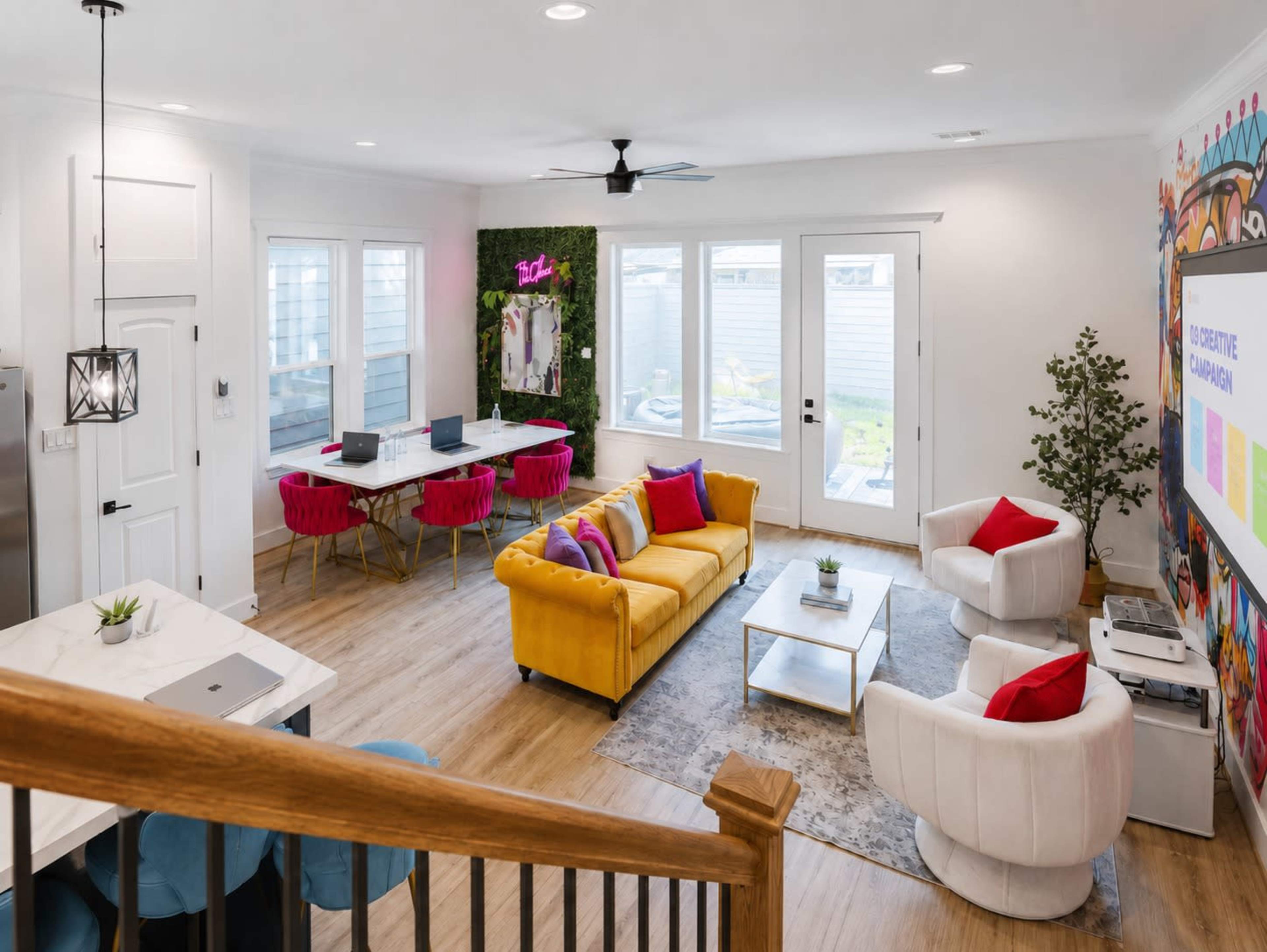 The image shows a modern living space that includes a yellow sofa, white armchairs, a glass coffee table, and a dining area with a long table and chairs.