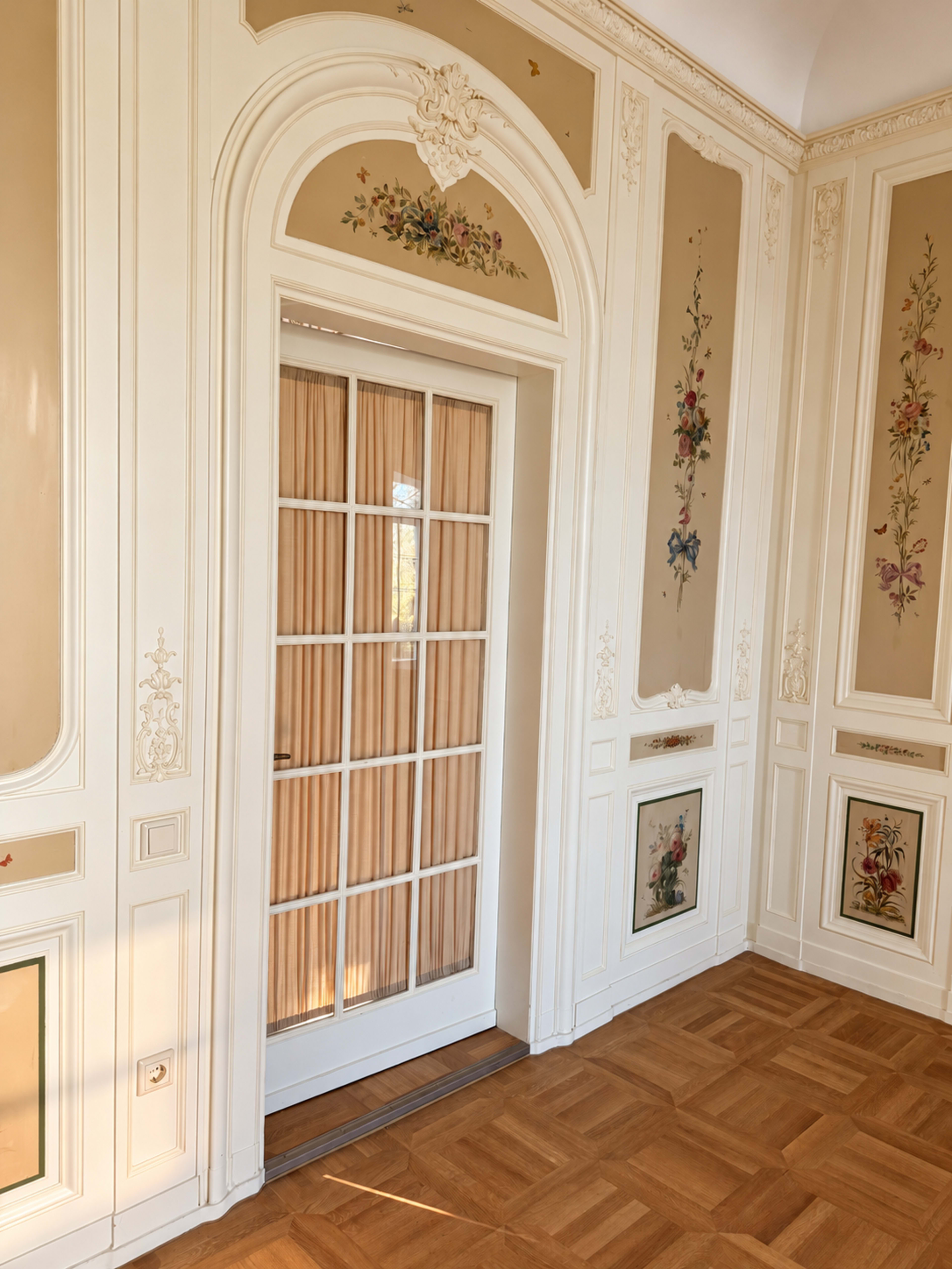 The image shows an elegantly designed room featuring a door with glass panels and floral decorations on the walls.