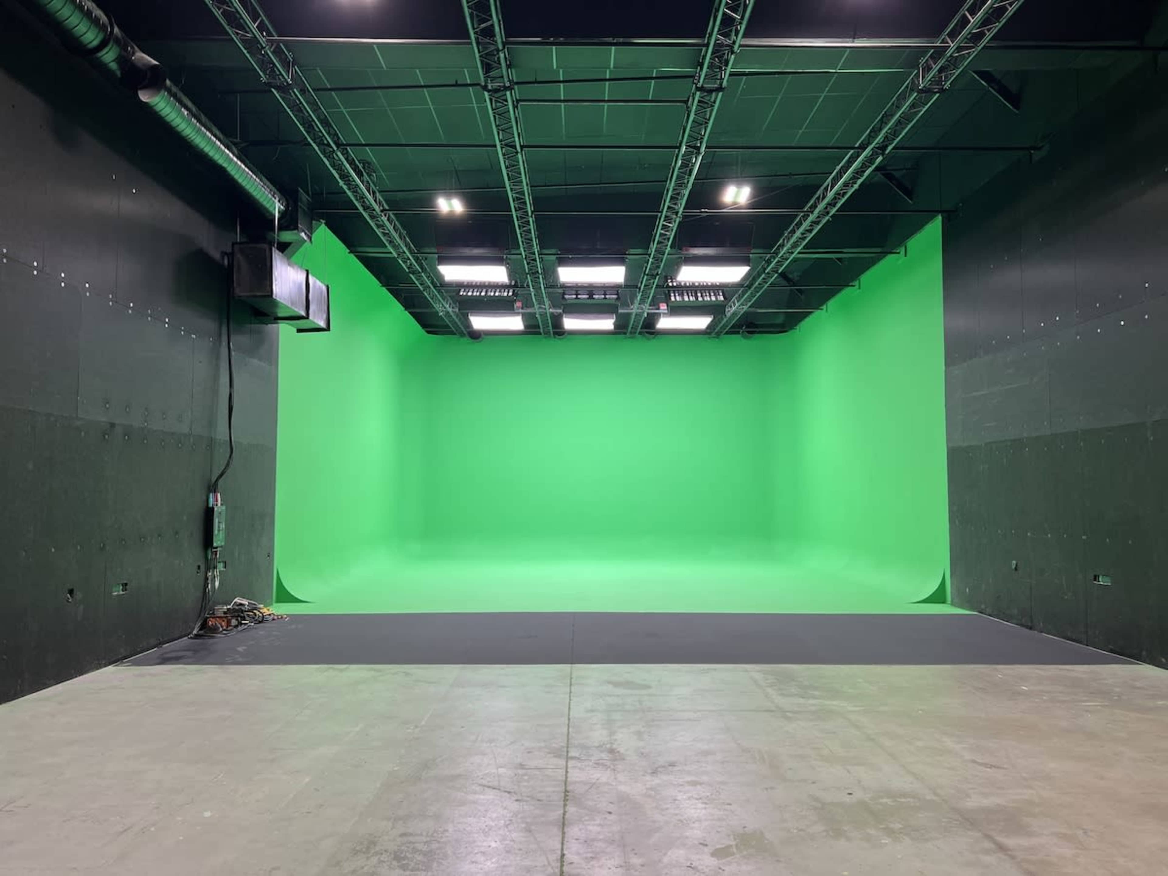 An empty studio space with a large green backdrop and a flat floor.