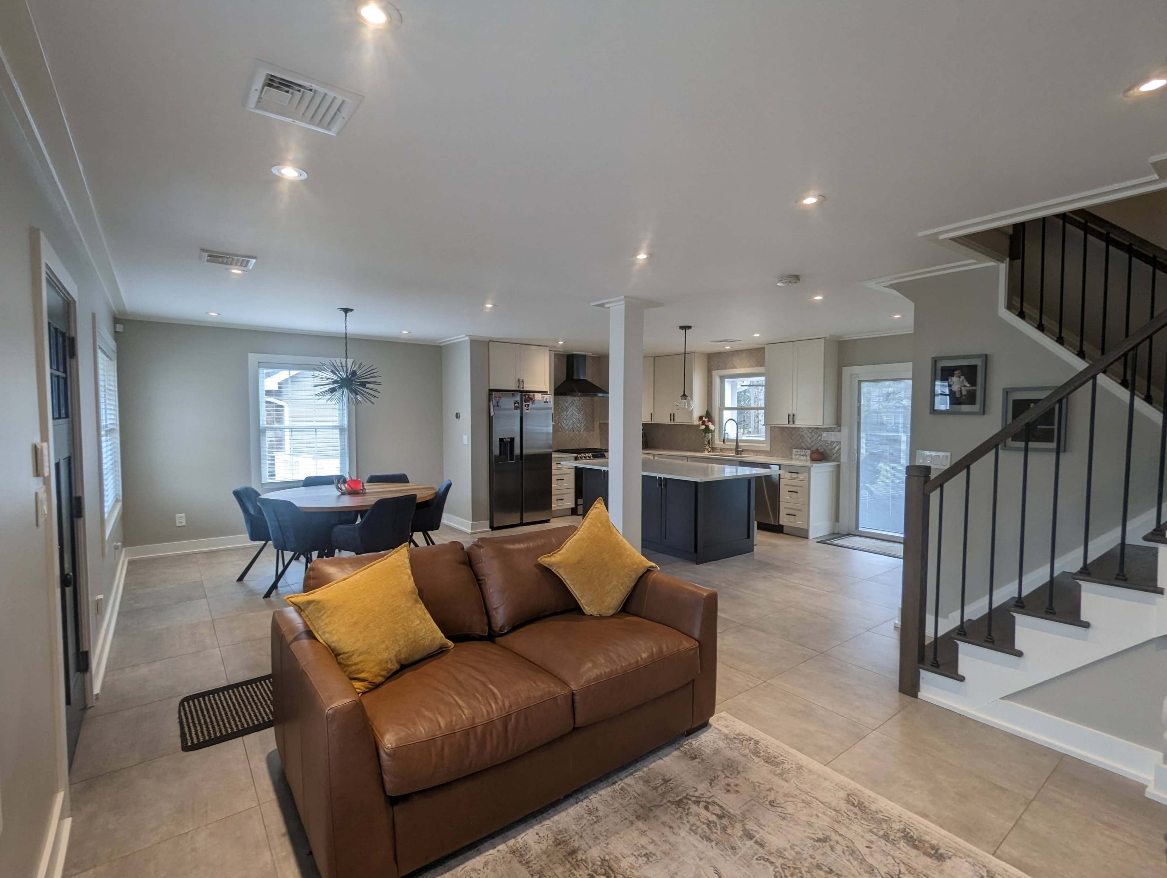 An open-concept living area with a brown couch, a dining table, and a kitchen in a modern home.