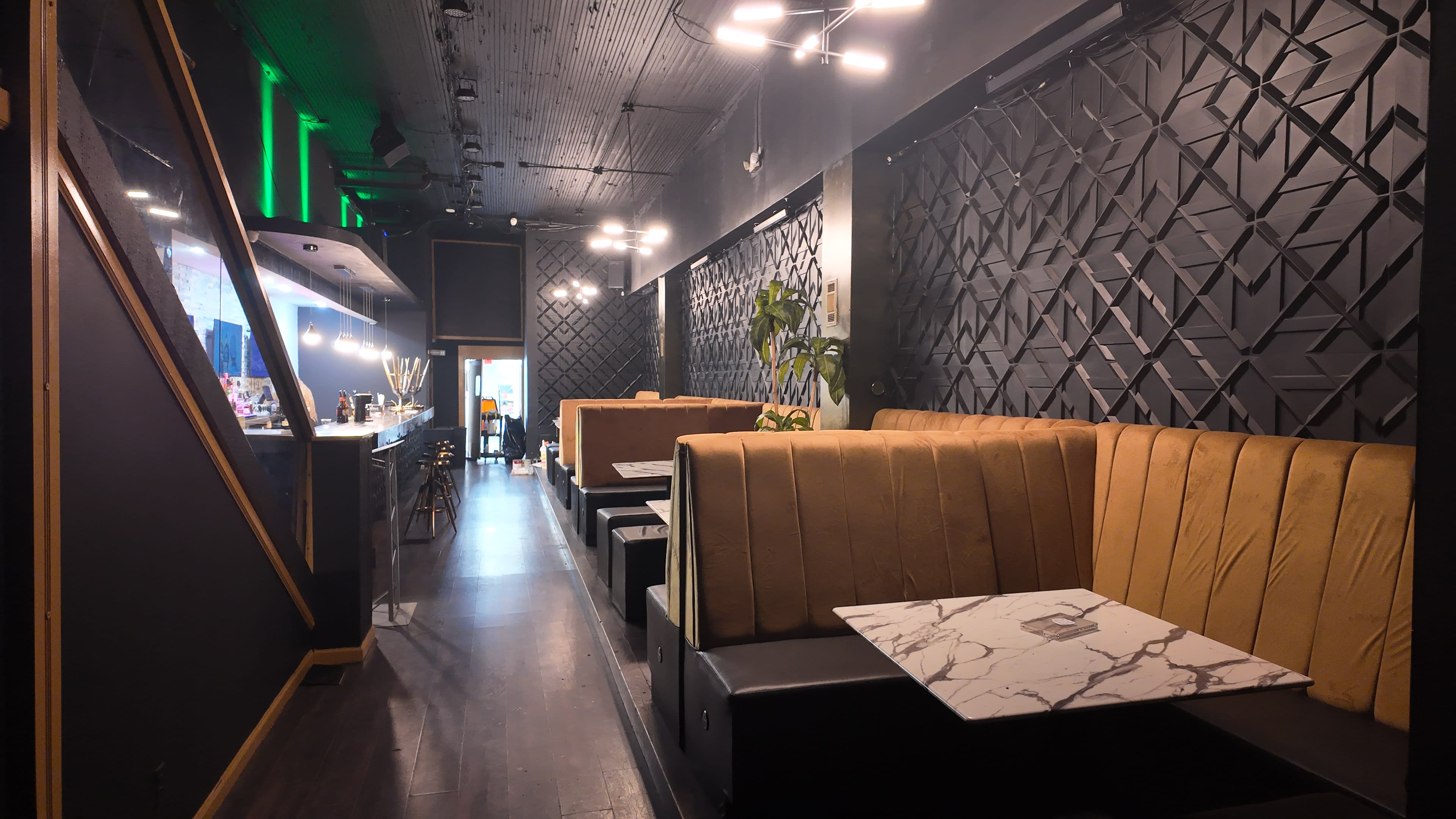 The image shows a modern restaurant interior featuring plush seating booths with a marble-topped table, illuminated by overhead lights.
