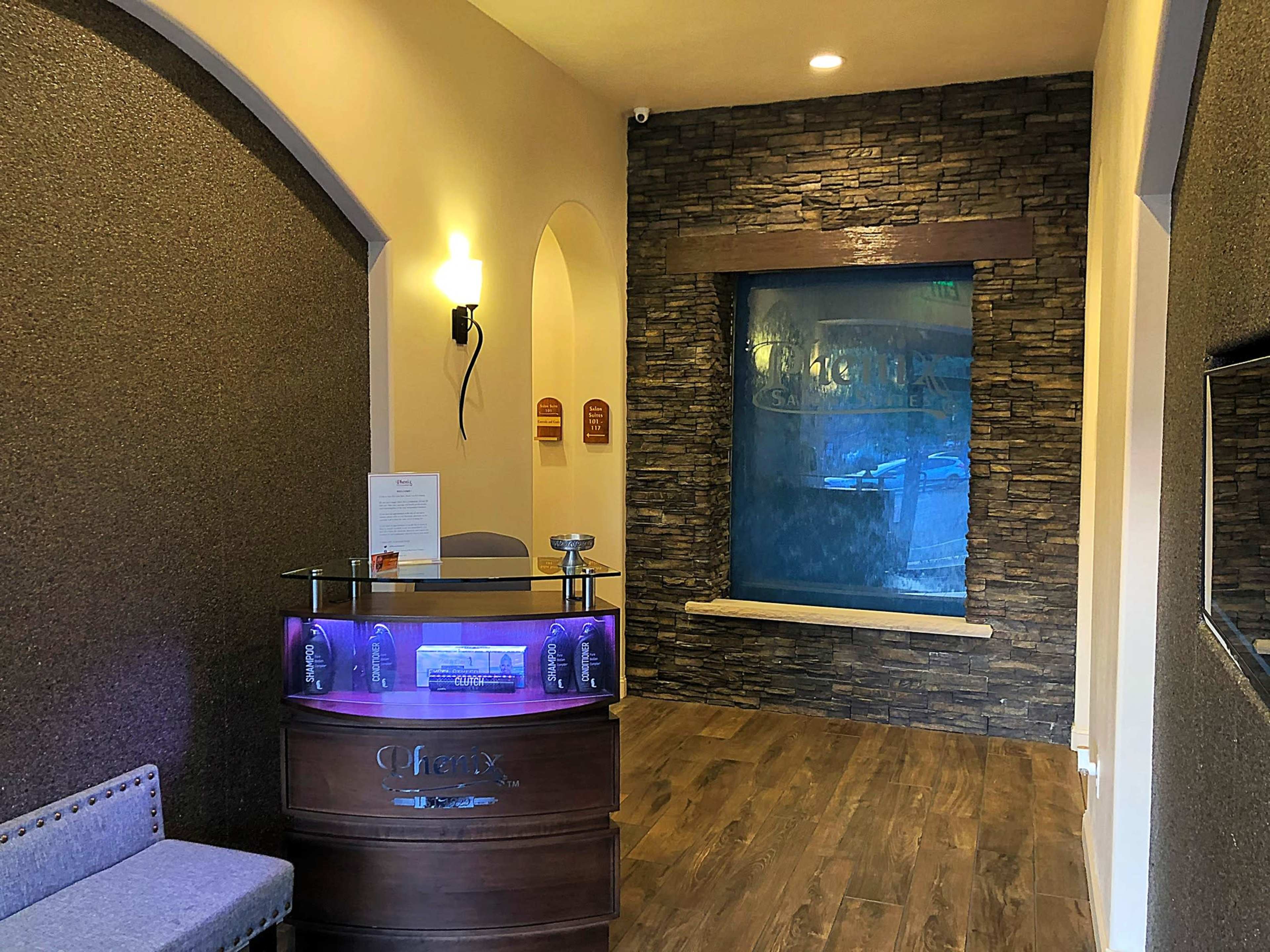 A reception area featuring a modern front desk, stone wall accents, and a water feature in the background.