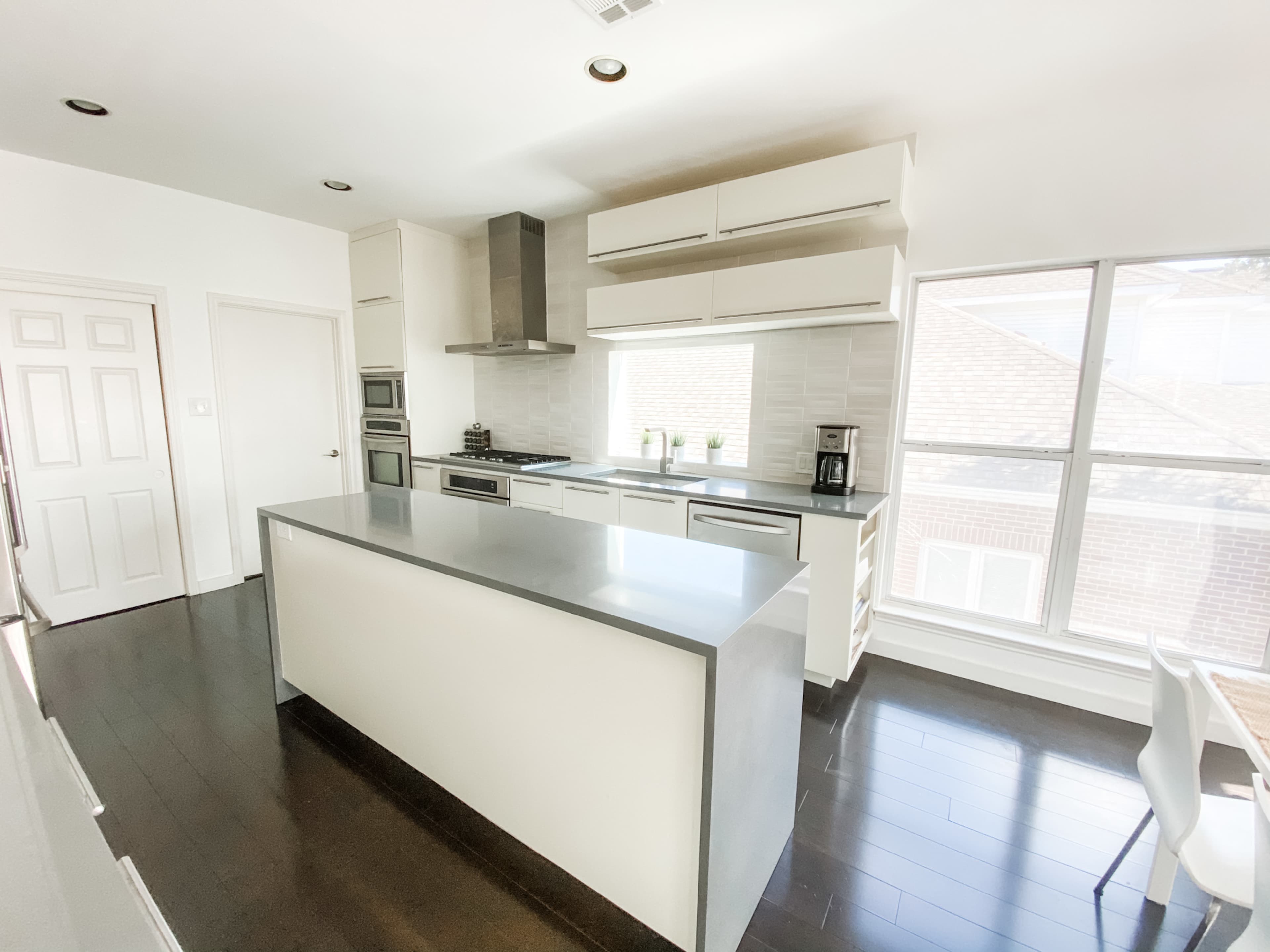 A modern kitchen with a large island, stainless steel appliances, and ample natural light coming through the windows.