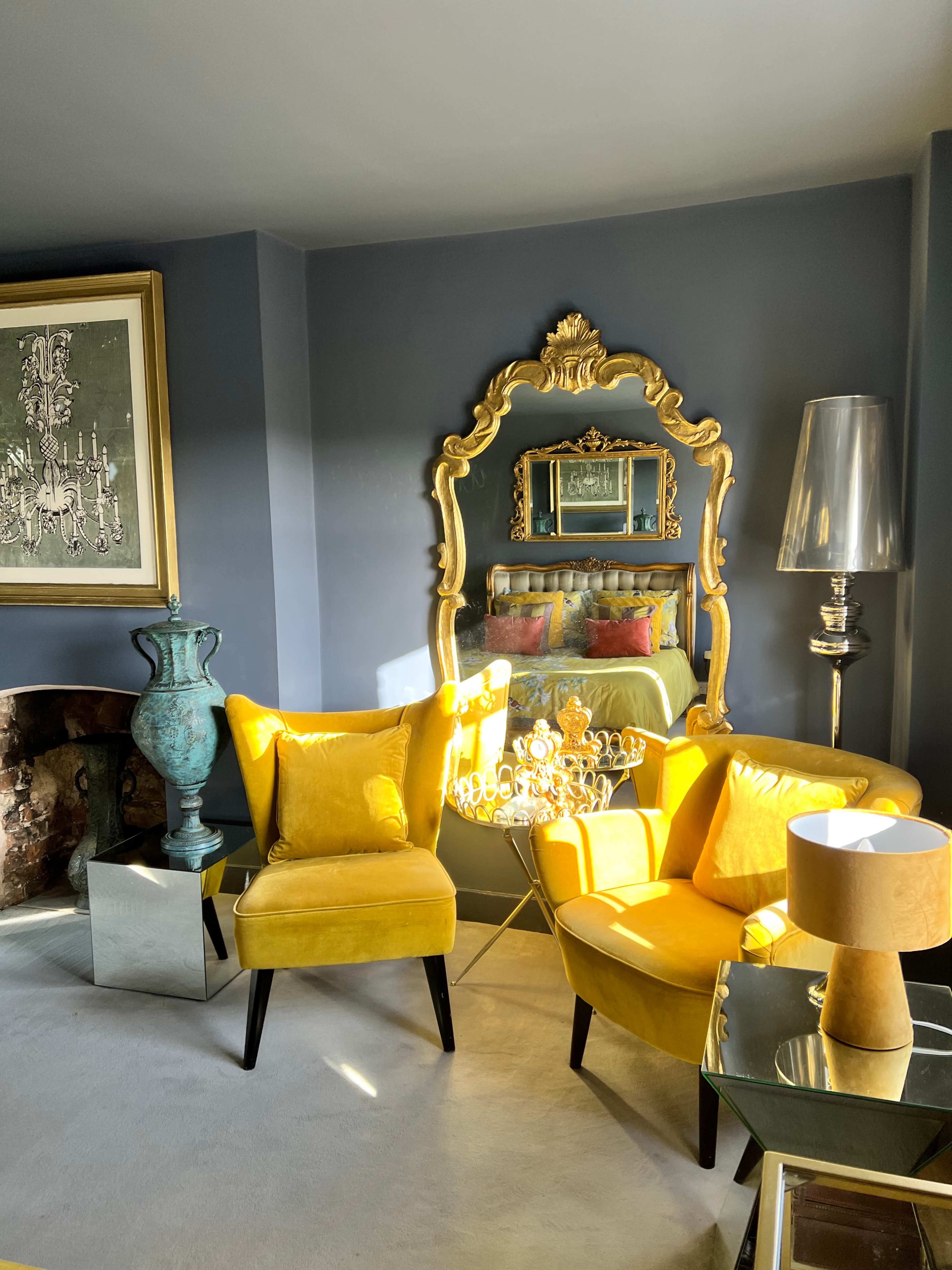 A stylish living room with bright yellow furniture, a decorative mirror, and a mix of modern and vintage decor.