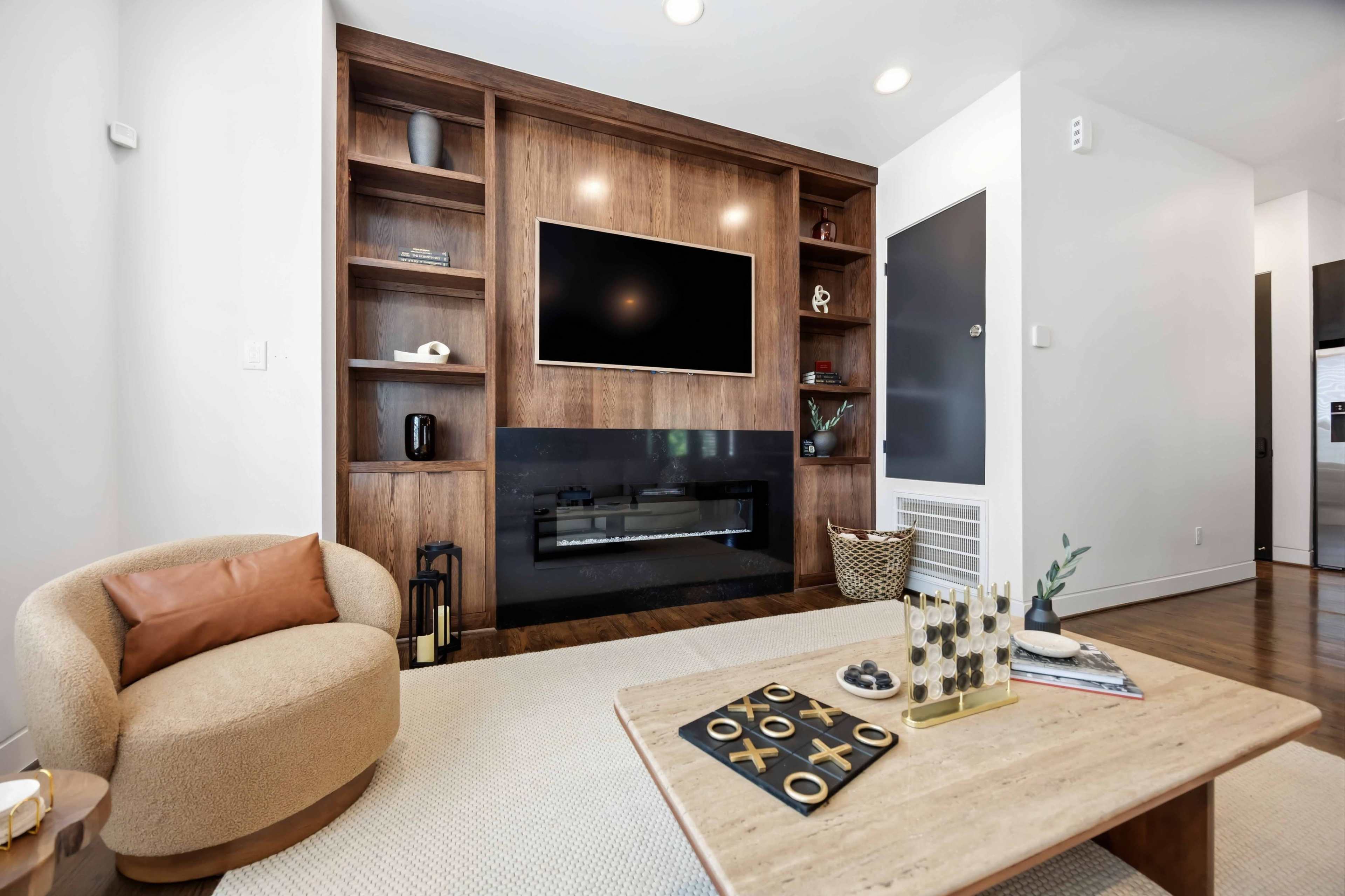The image shows a modern living room with a wooden feature wall, a mounted television, and a cozy circular chair beside a coffee table.