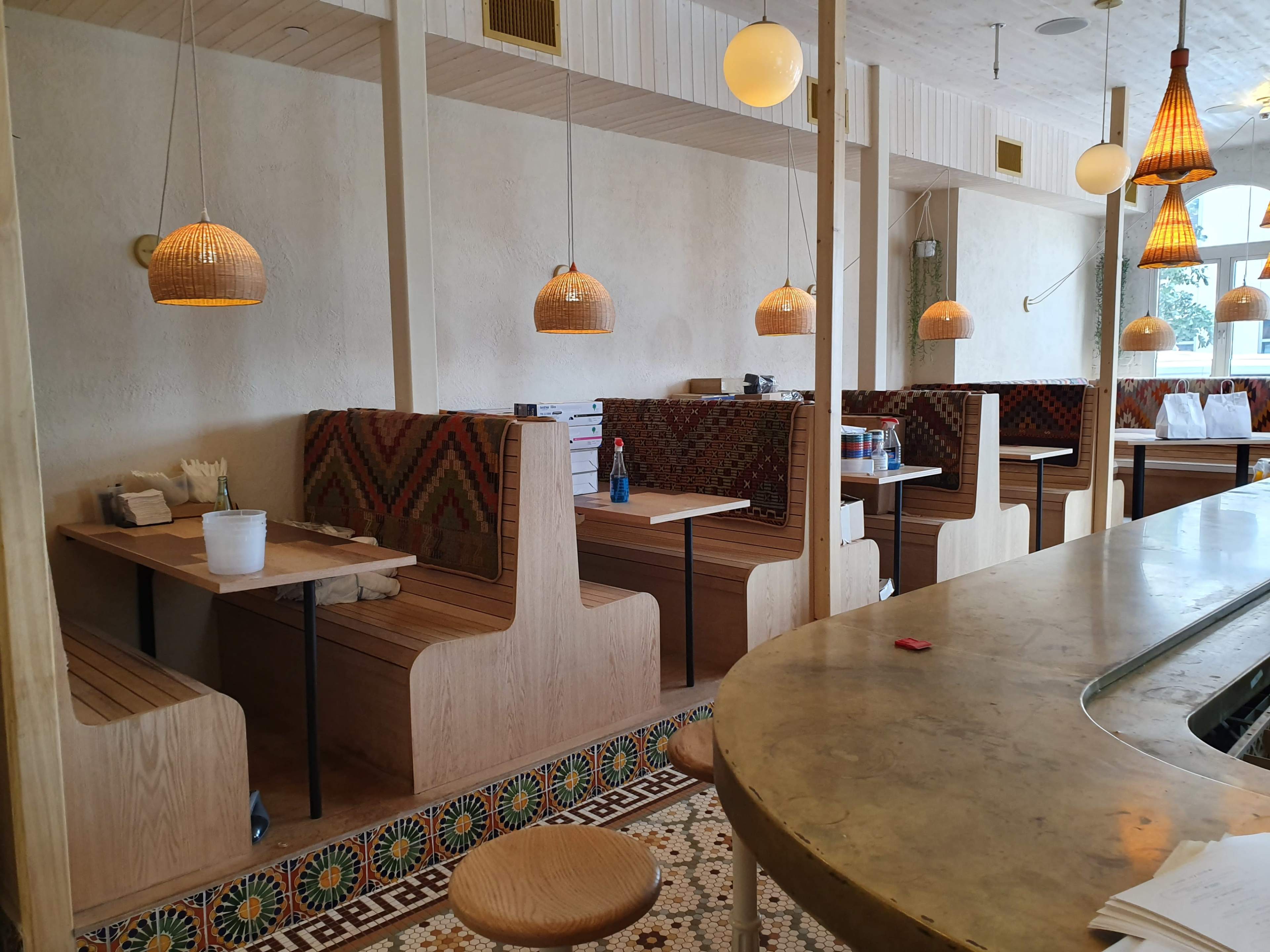 A dining area with wooden booths, pendant lights, and a patterned tile floor.