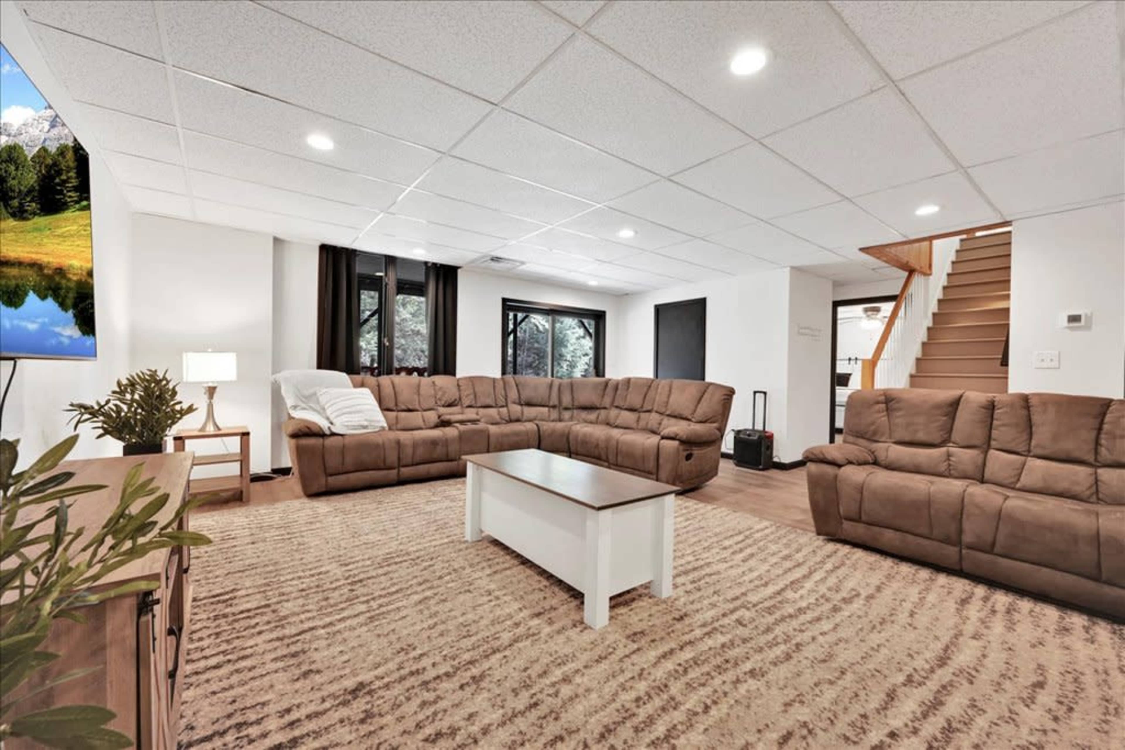 A spacious living room with a sectional sofa, a coffee table, and stairs leading to another level.