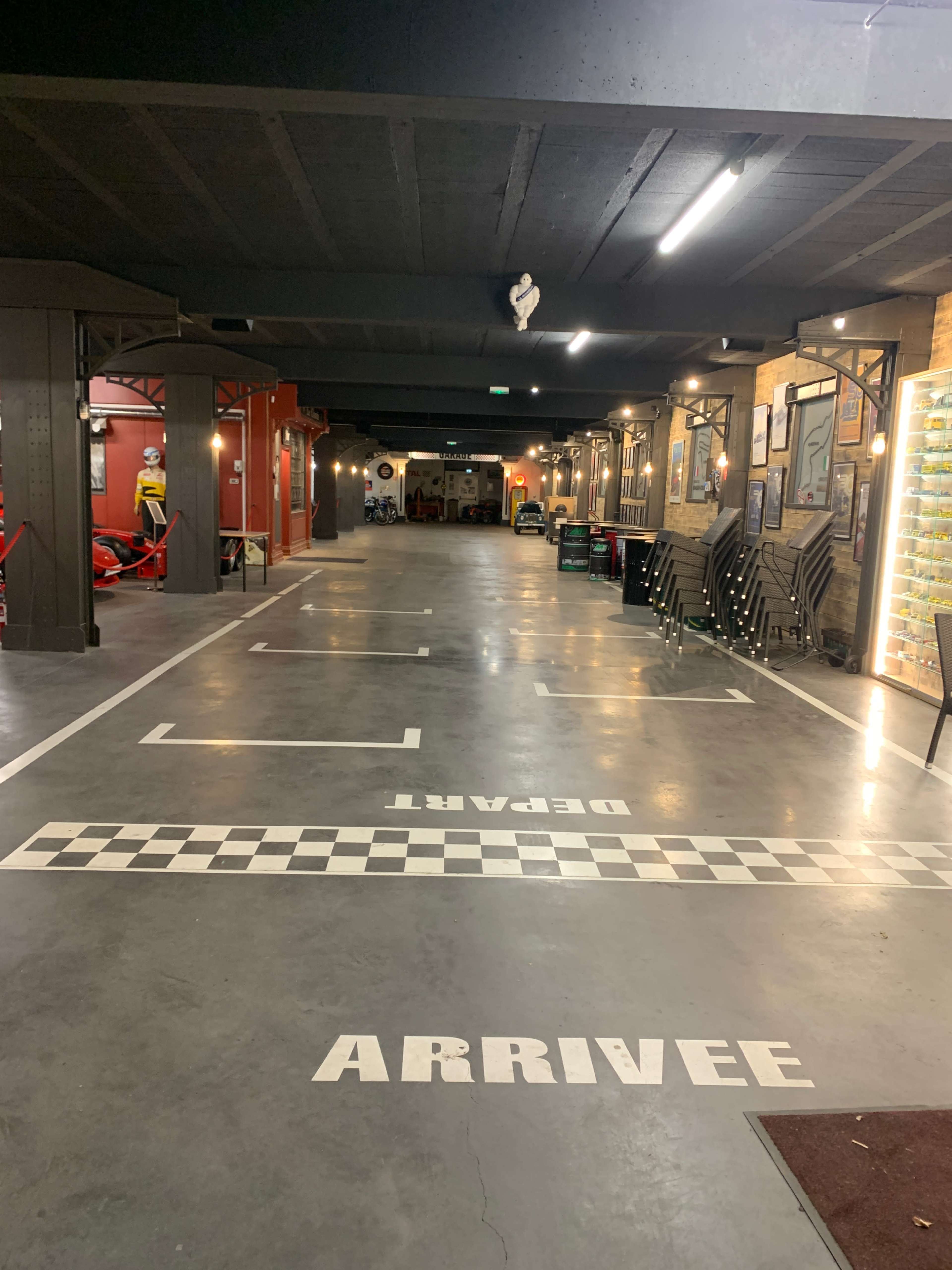 The image shows an empty parking garage with markings for "ARRIVEE" and "DEPART" on the floor and a checkered pattern along the ground.