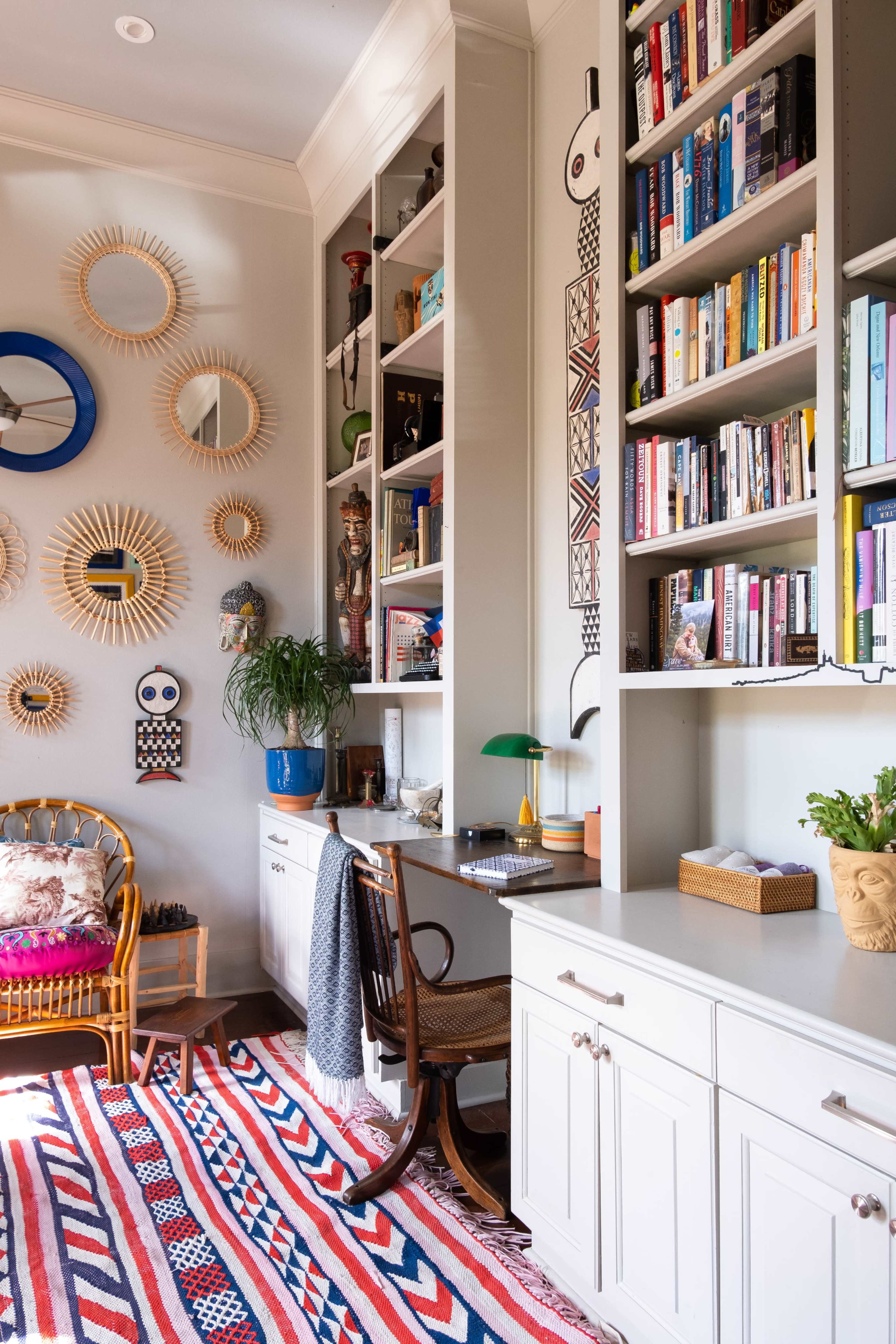 A cozy reading nook with built-in shelves filled with books, decorative mirrors on the wall, and a patterned rug on the floor.