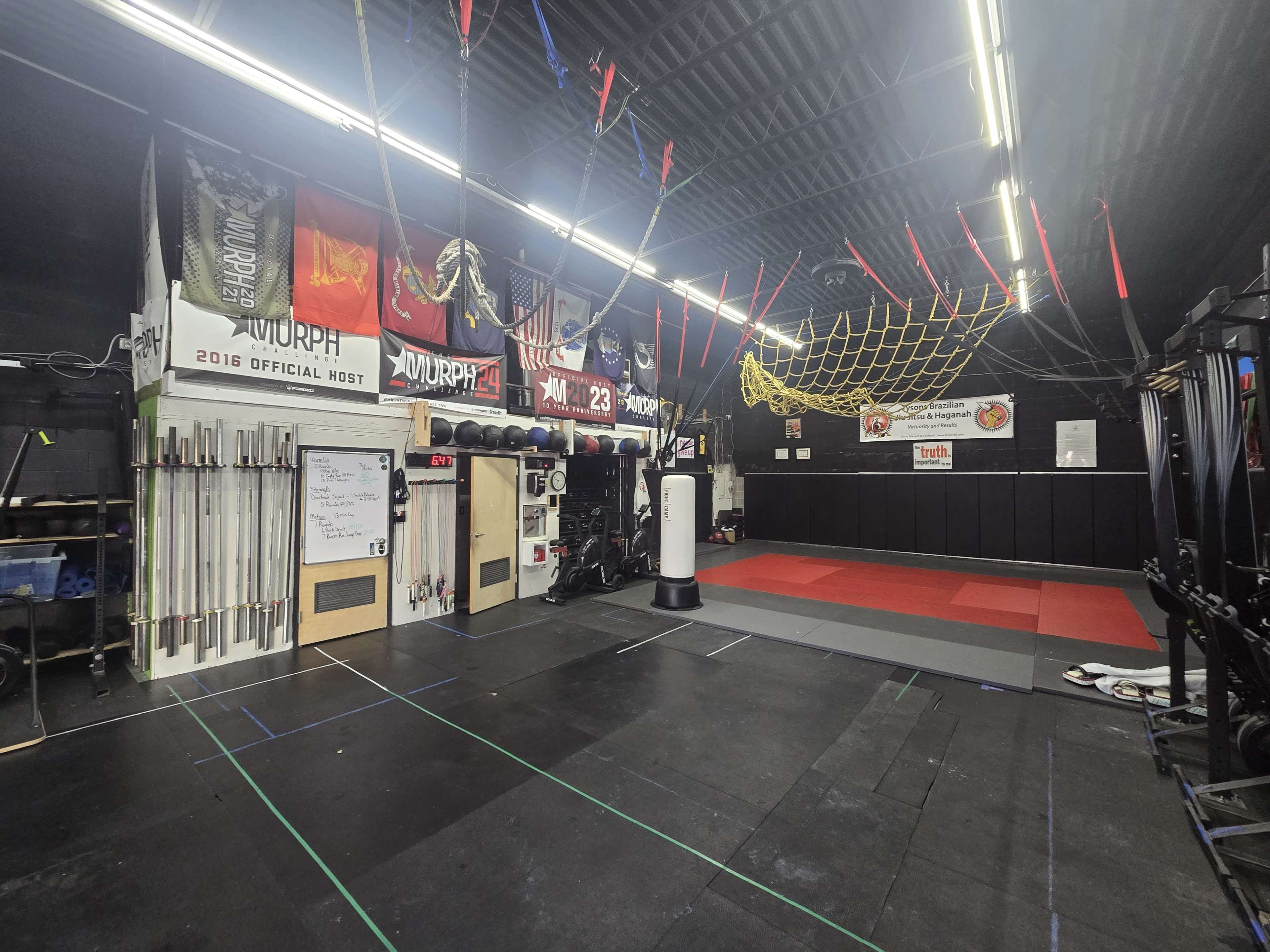 The image shows a fitness gym with various equipment, including weights, a punching bag, and fitness mats, illuminated by overhead lights.
