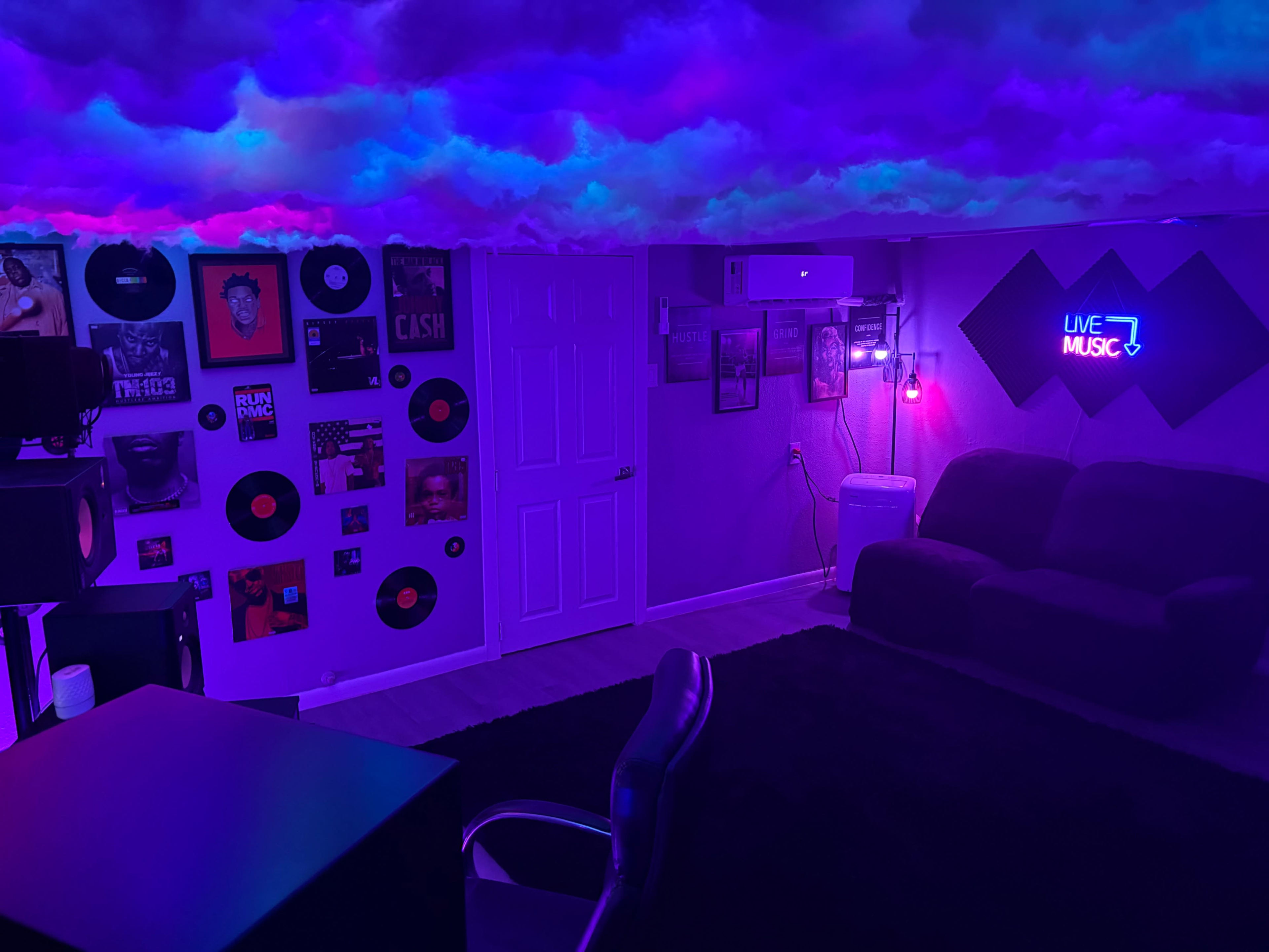 The image shows a dimly lit room with a purple cloud-like ceiling, decorated with music-related posters and vinyl records, along with a couch and a desk chair.