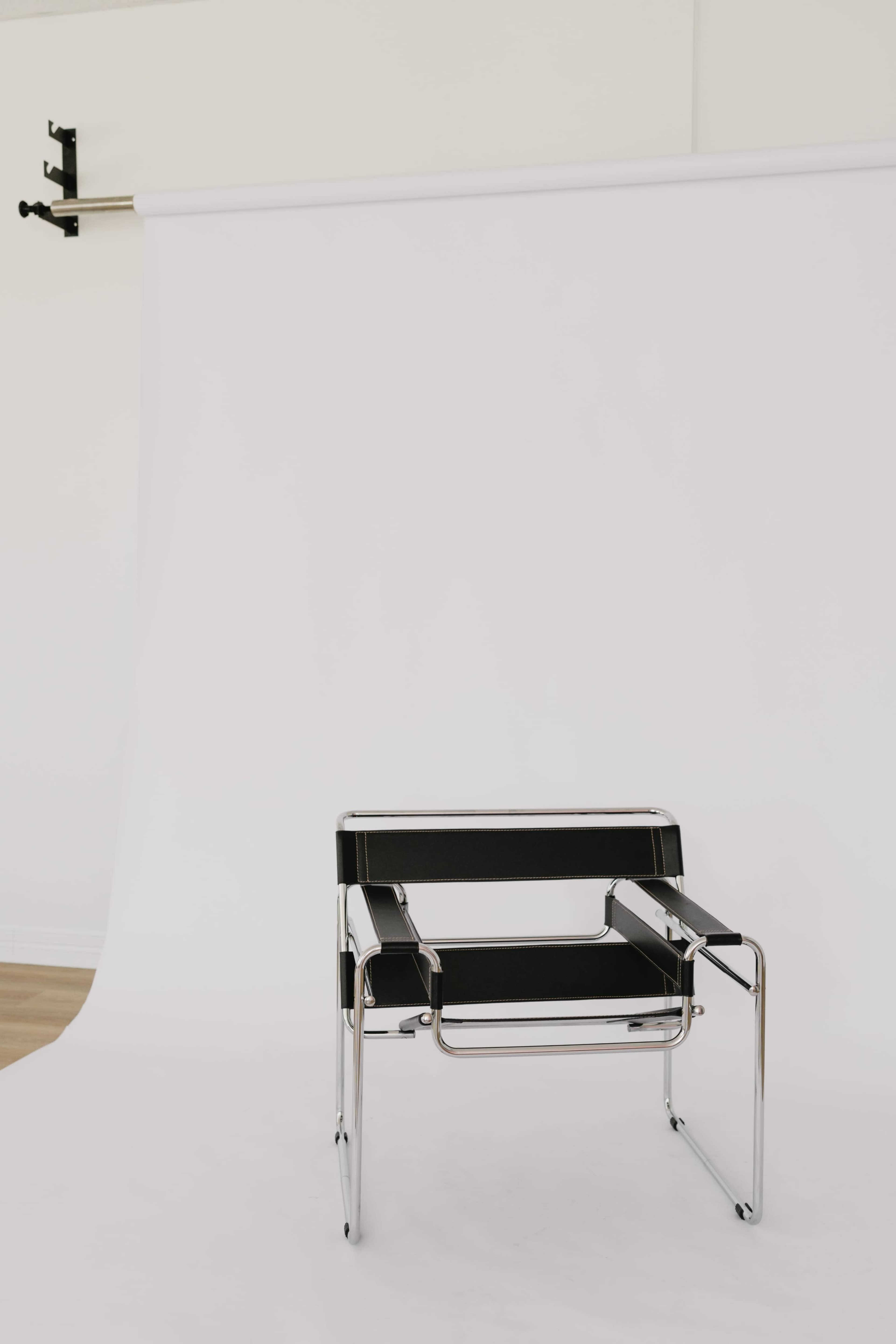 A modern black and chrome chair is positioned in front of a white backdrop.