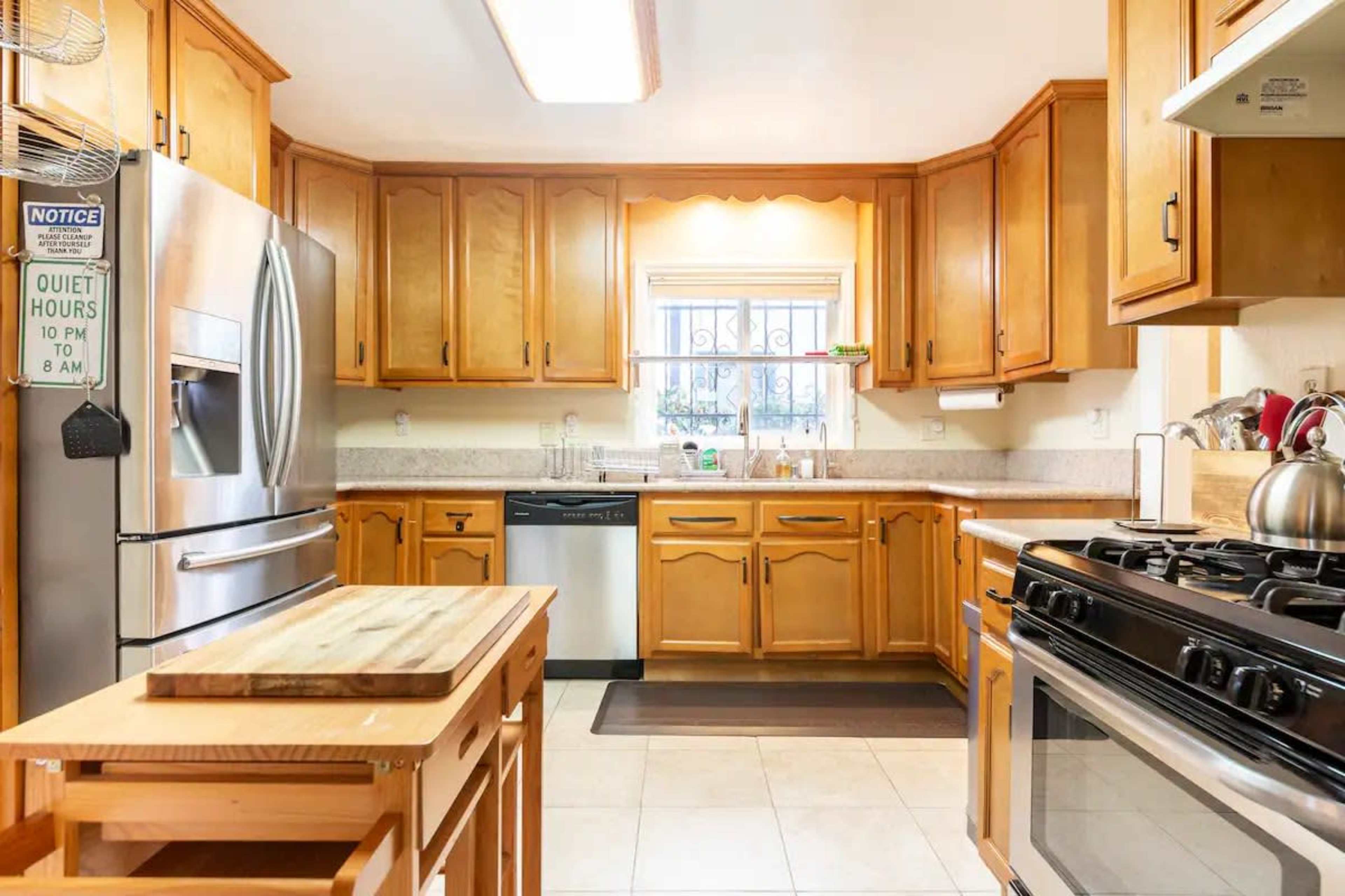 A kitchen features wooden cabinets, stainless steel appliances, and a central island with a countertop.