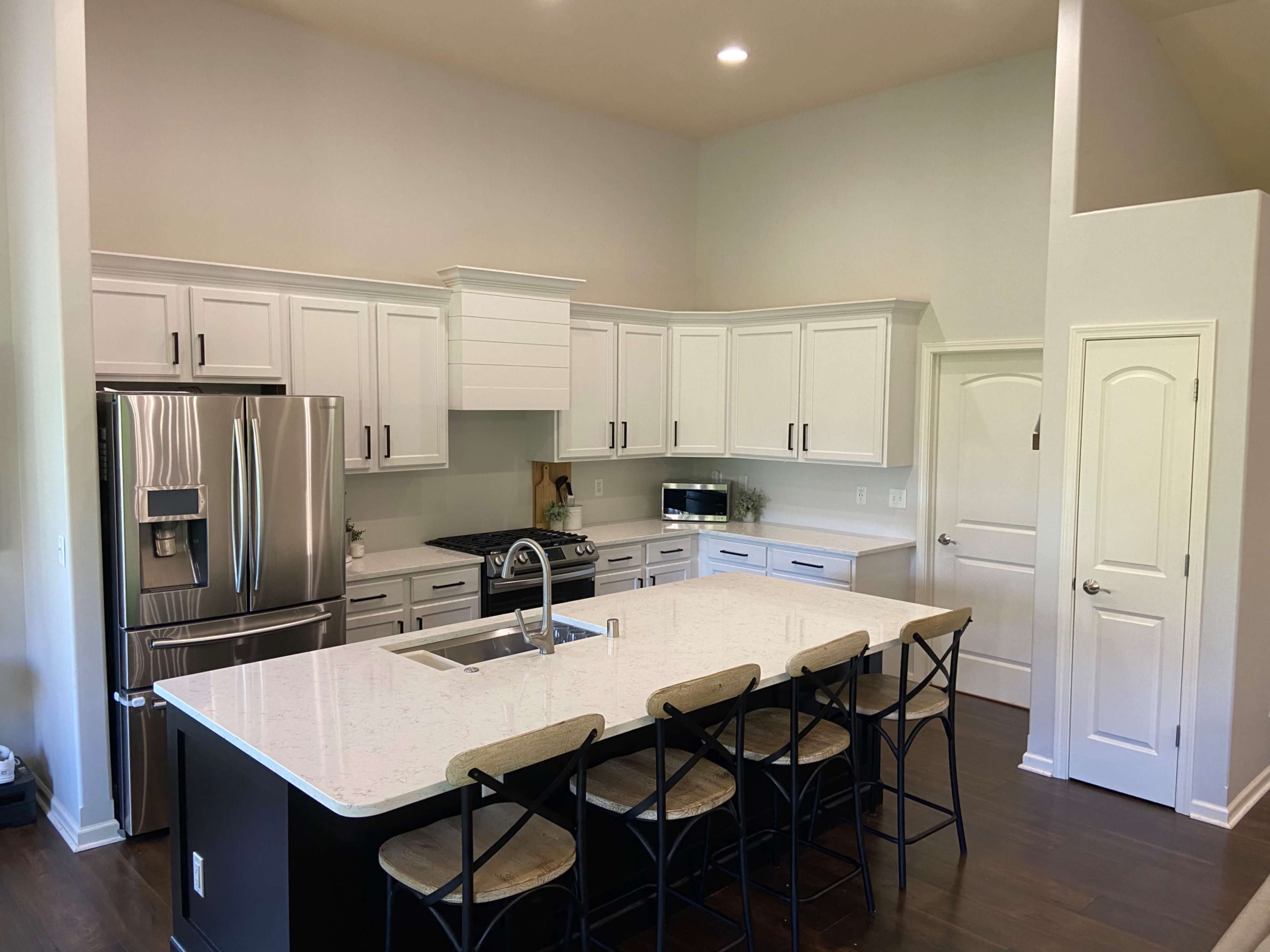 A modern kitchen features white cabinetry, black countertops, and a large island with bar seating.