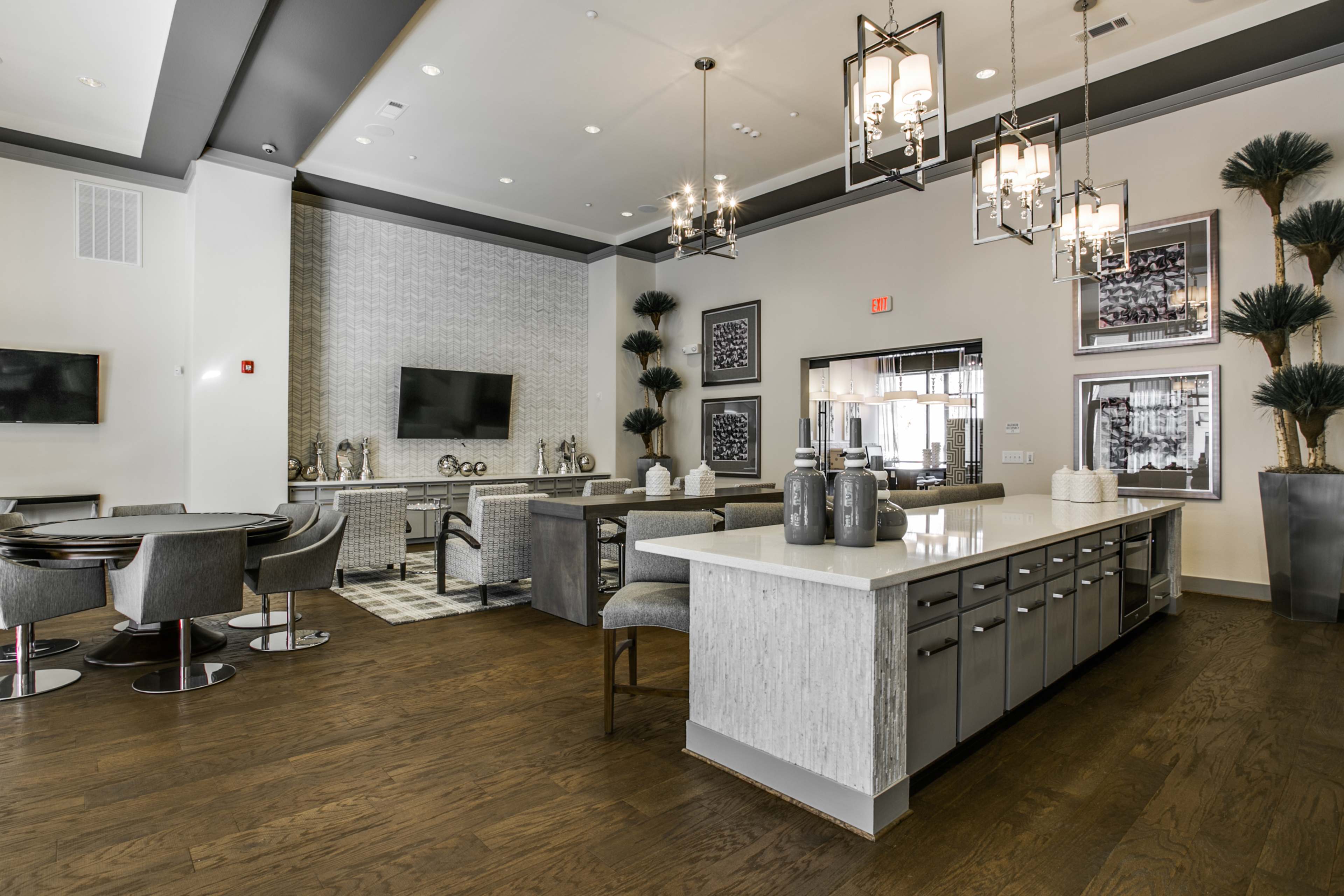 A modern kitchen and dining area features gray cabinetry, a large island with bar seating, and stylish lighting.