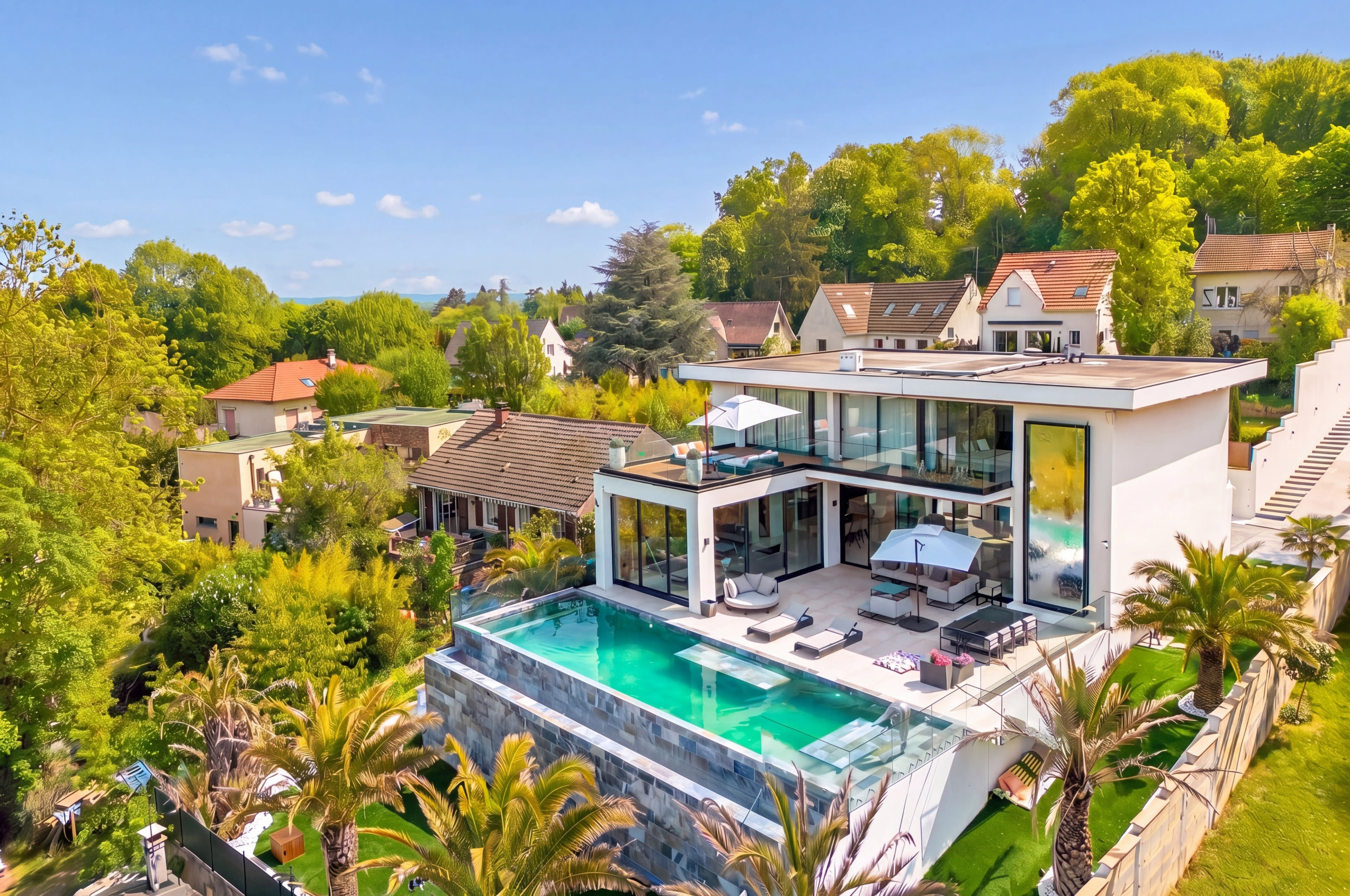 A modern two-story house with a swimming pool is surrounded by greenery and residential buildings.