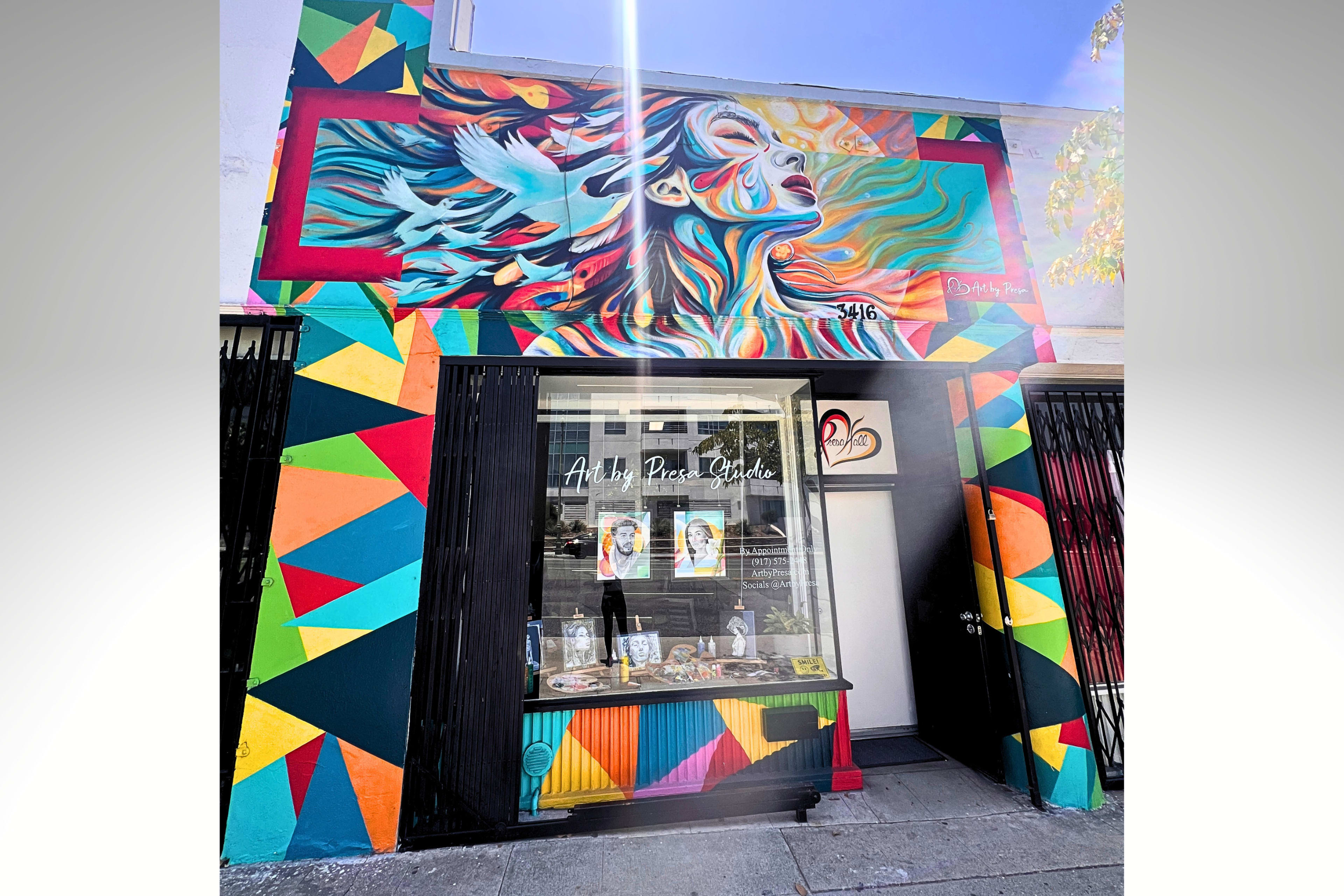 The image shows a colorful mural on a storefront featuring a woman with flowing hair, surrounded by vibrant geometric patterns.