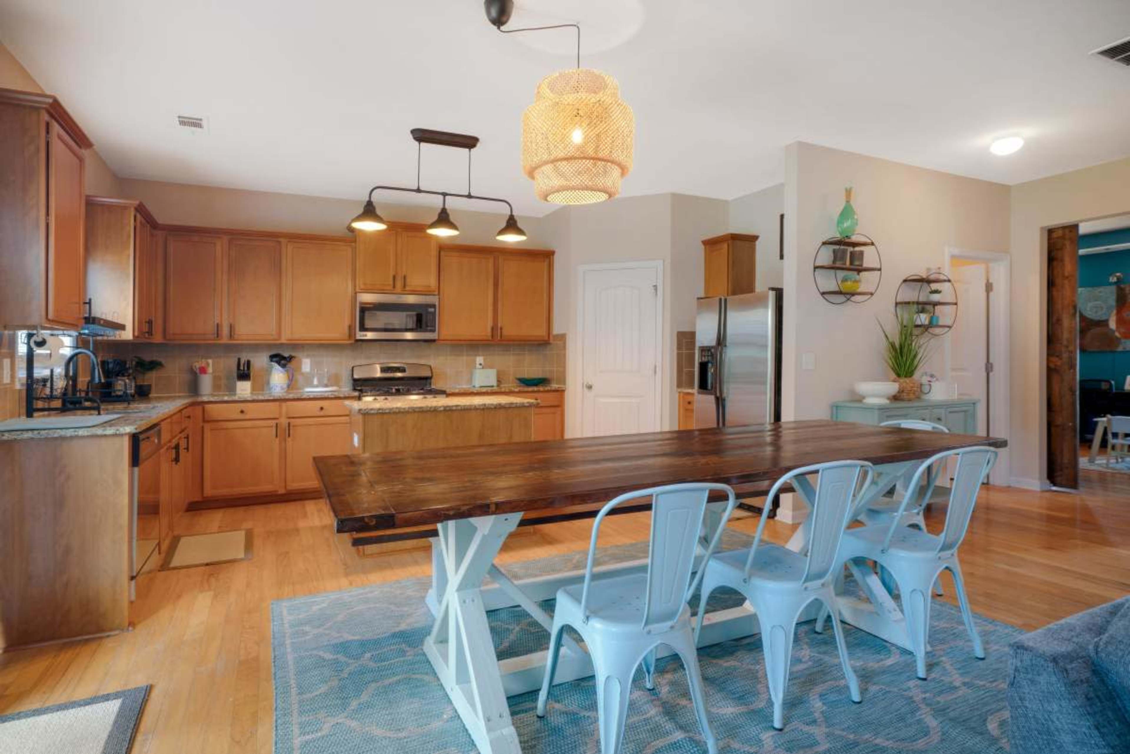 A spacious kitchen features wooden cabinets, stainless steel appliances, and a dining table with metal chairs.