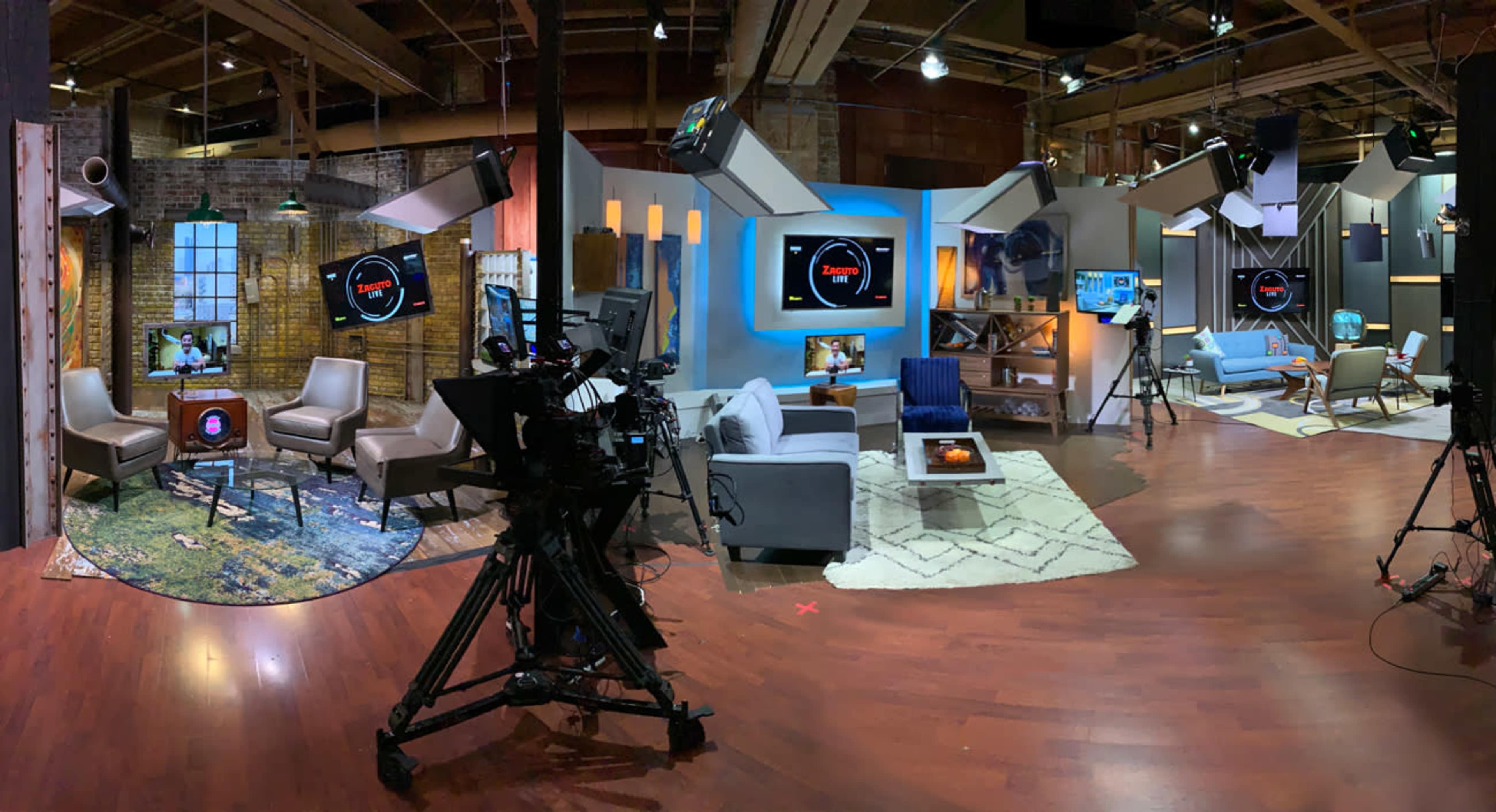 A television studio set with cameras, lighting equipment, and various seating areas arranged for a talk show.