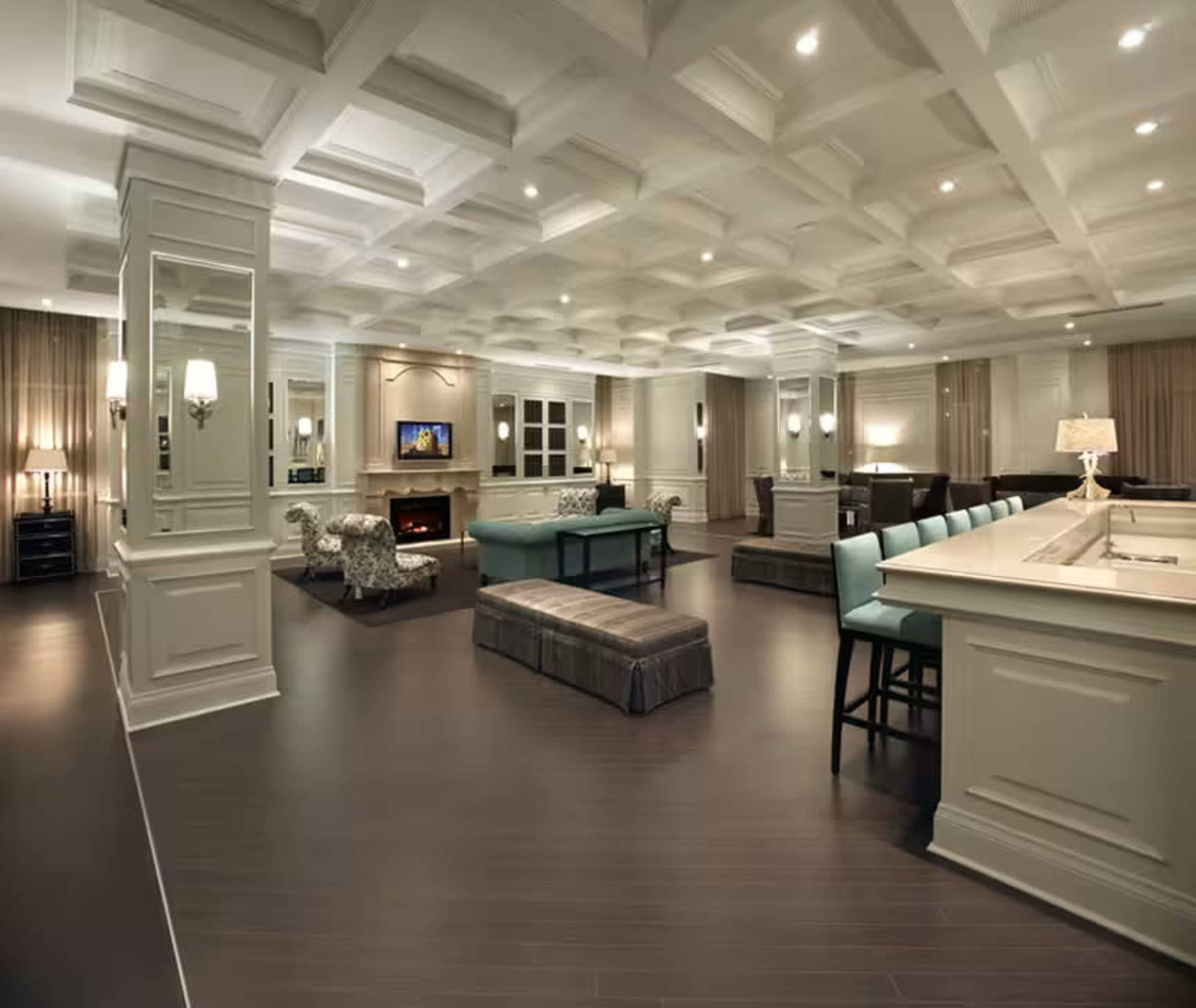 A spacious, well-lit interior room with coffered ceilings, modern furniture, and a large bar area.