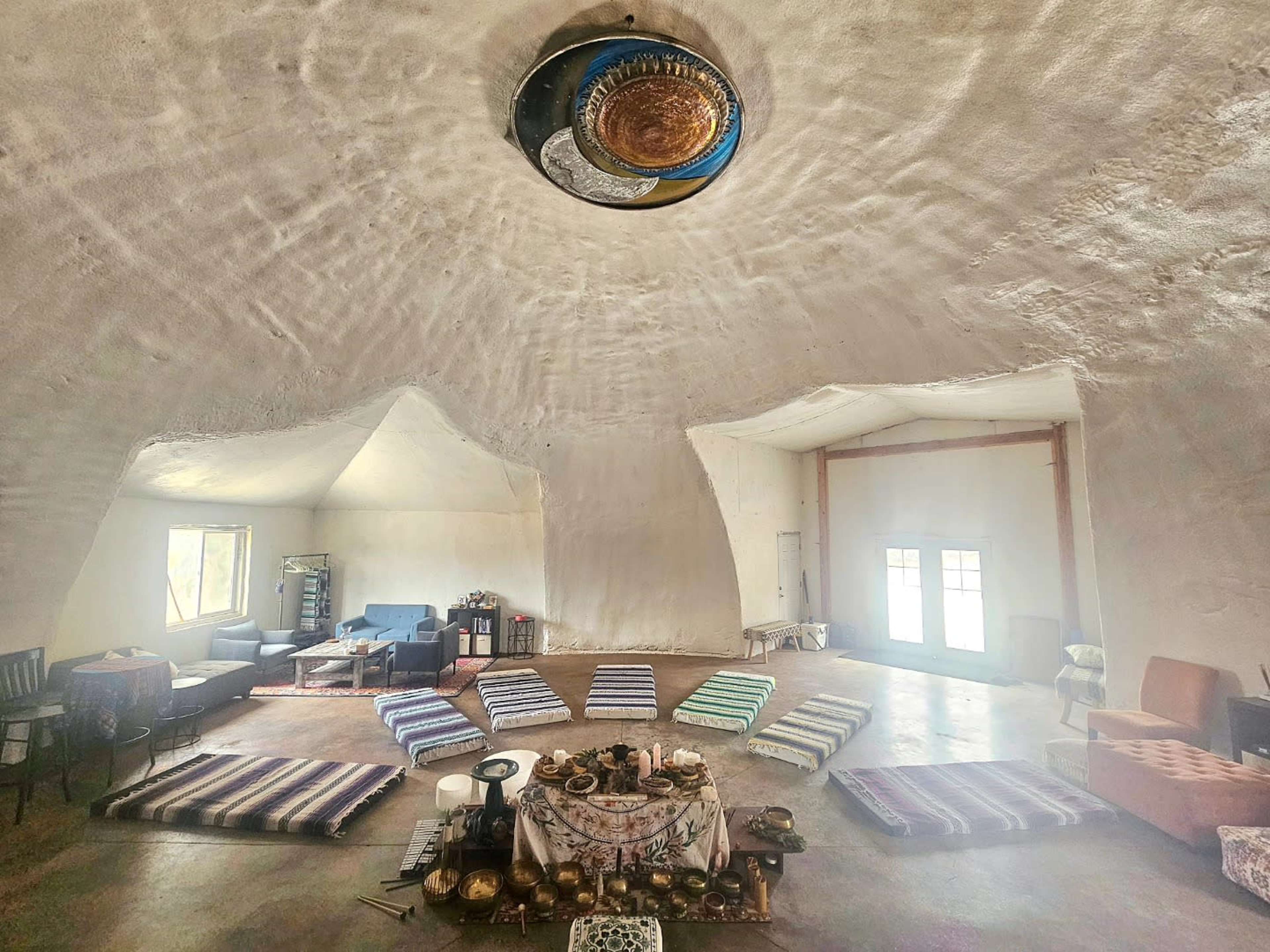 The image shows a spacious, dome-shaped room with a circular seating arrangement on the floor, surrounded by various furniture pieces.