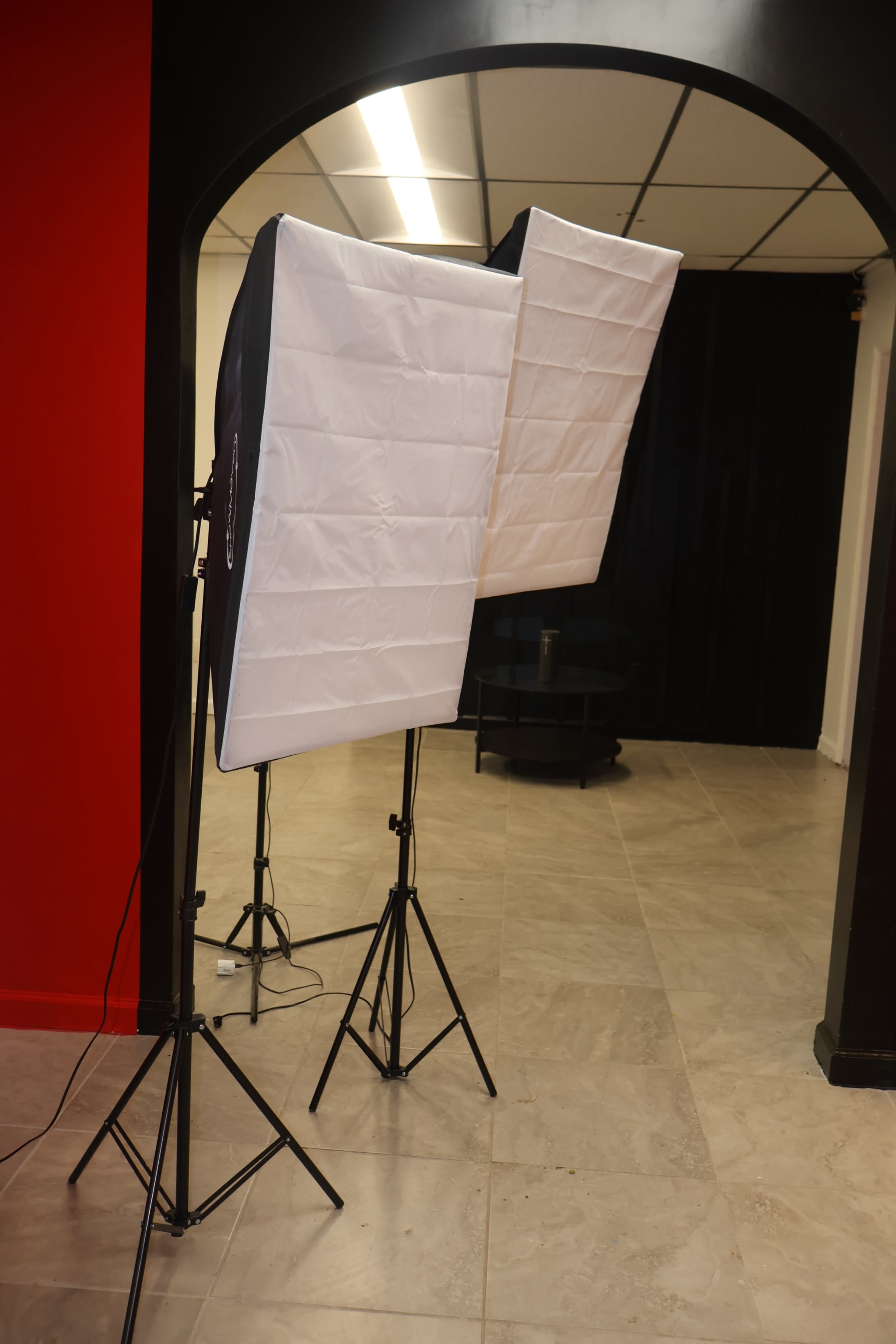 Two softbox lighting setups on stands are positioned in a studio space with a red and black color scheme.