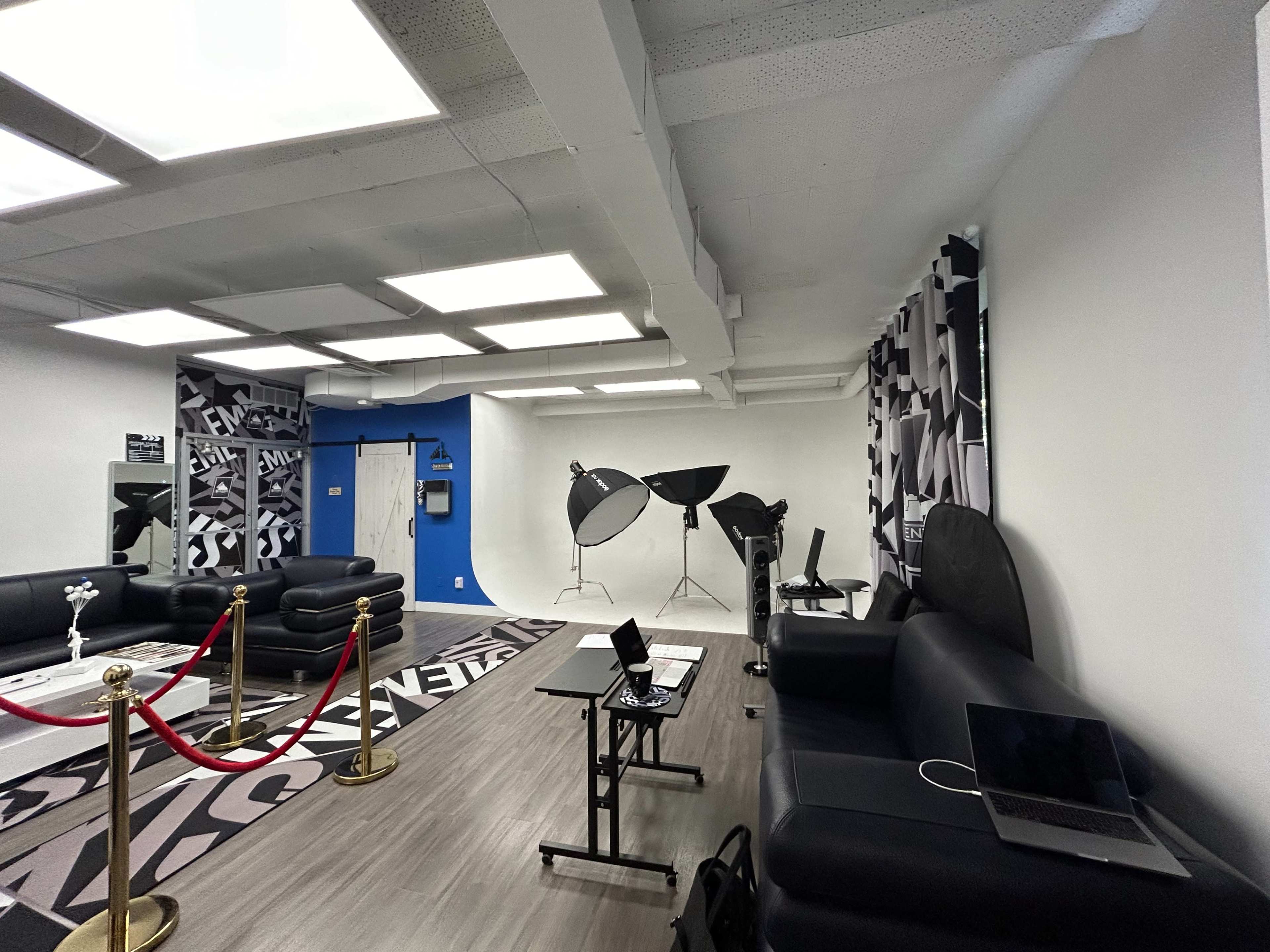 The room features black leather furniture, modern lighting fixtures, and photography equipment, with a stylish rug on the floor.