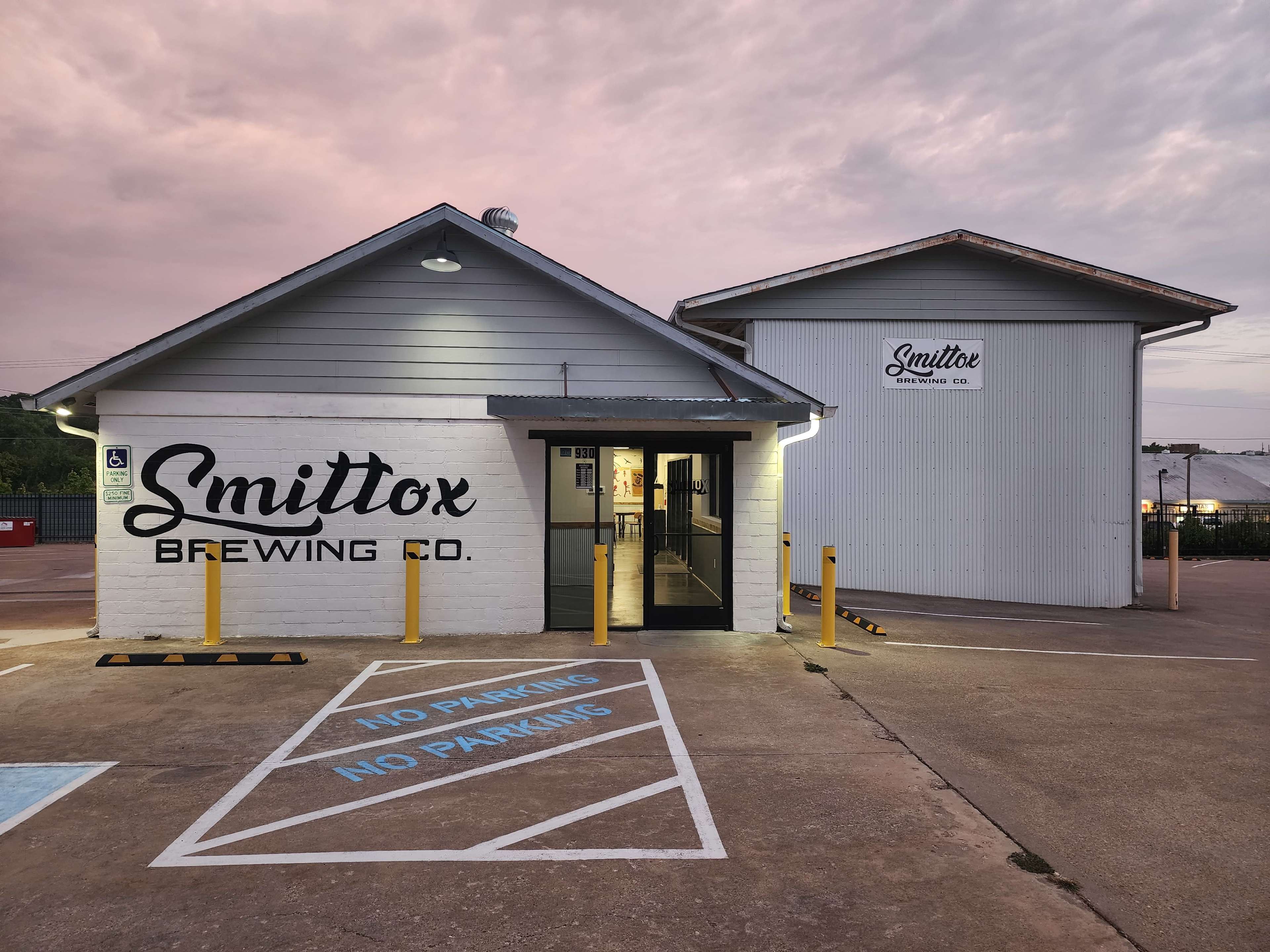 The image shows a brewing company building with a white exterior, featuring the name "Smittox Brewing Co." prominently displayed.