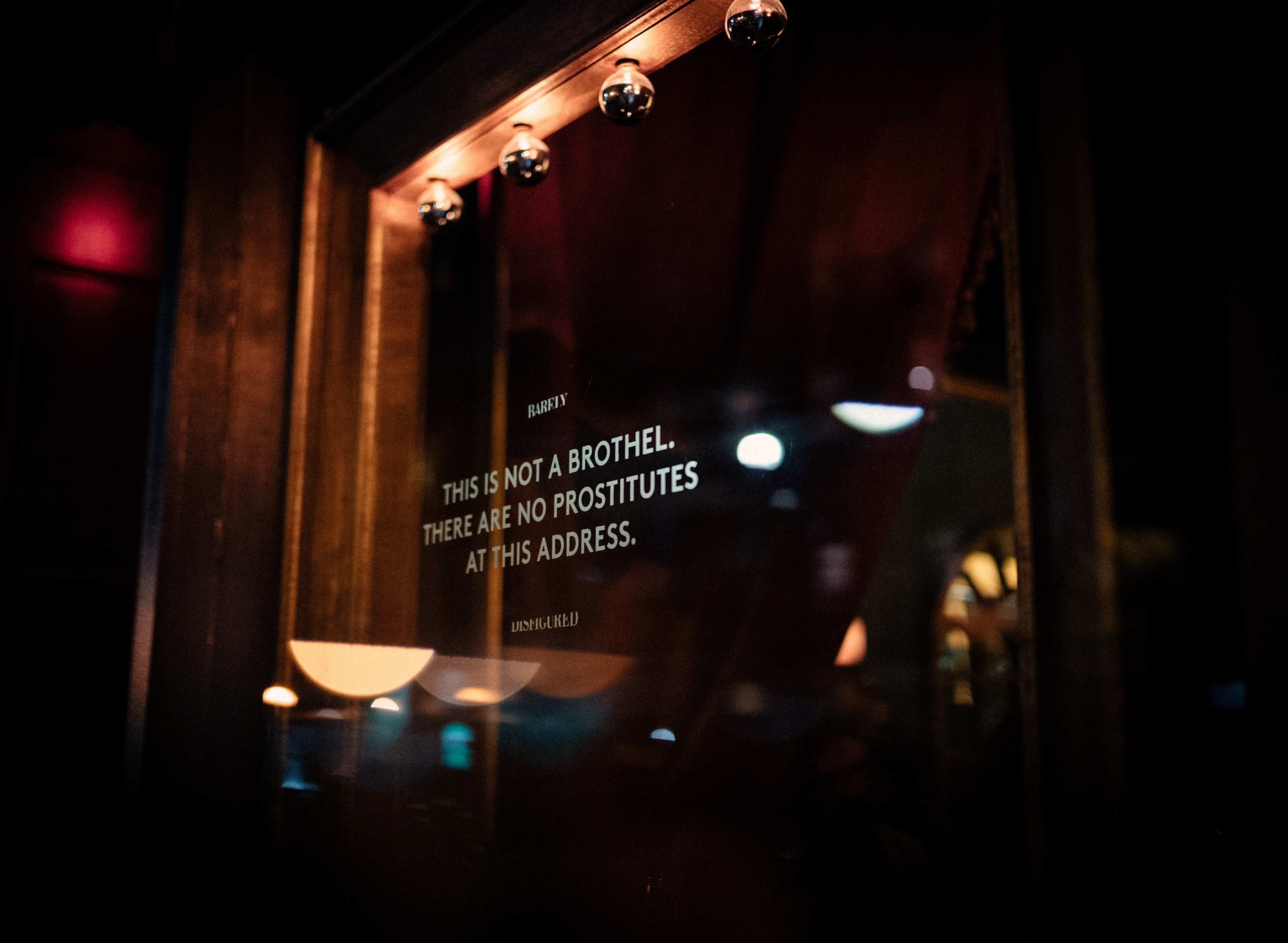 A sign in a window states, "THIS IS NOT A BROTHEL. THERE ARE NO PROSTITUTES AT THIS ADDRESS."