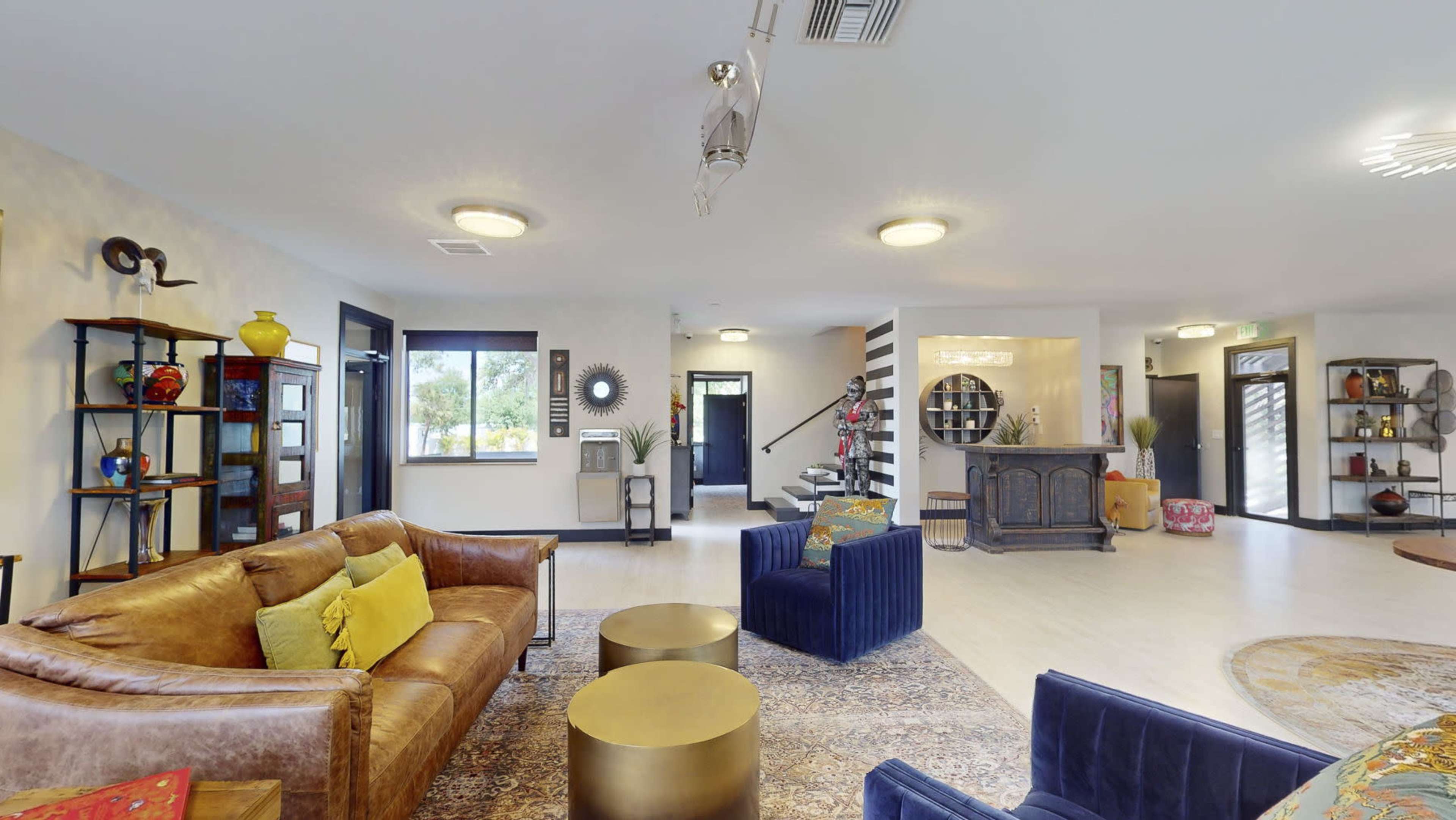 A spacious living area with a mix of seating options, decorative shelves, and a staircase in the background.