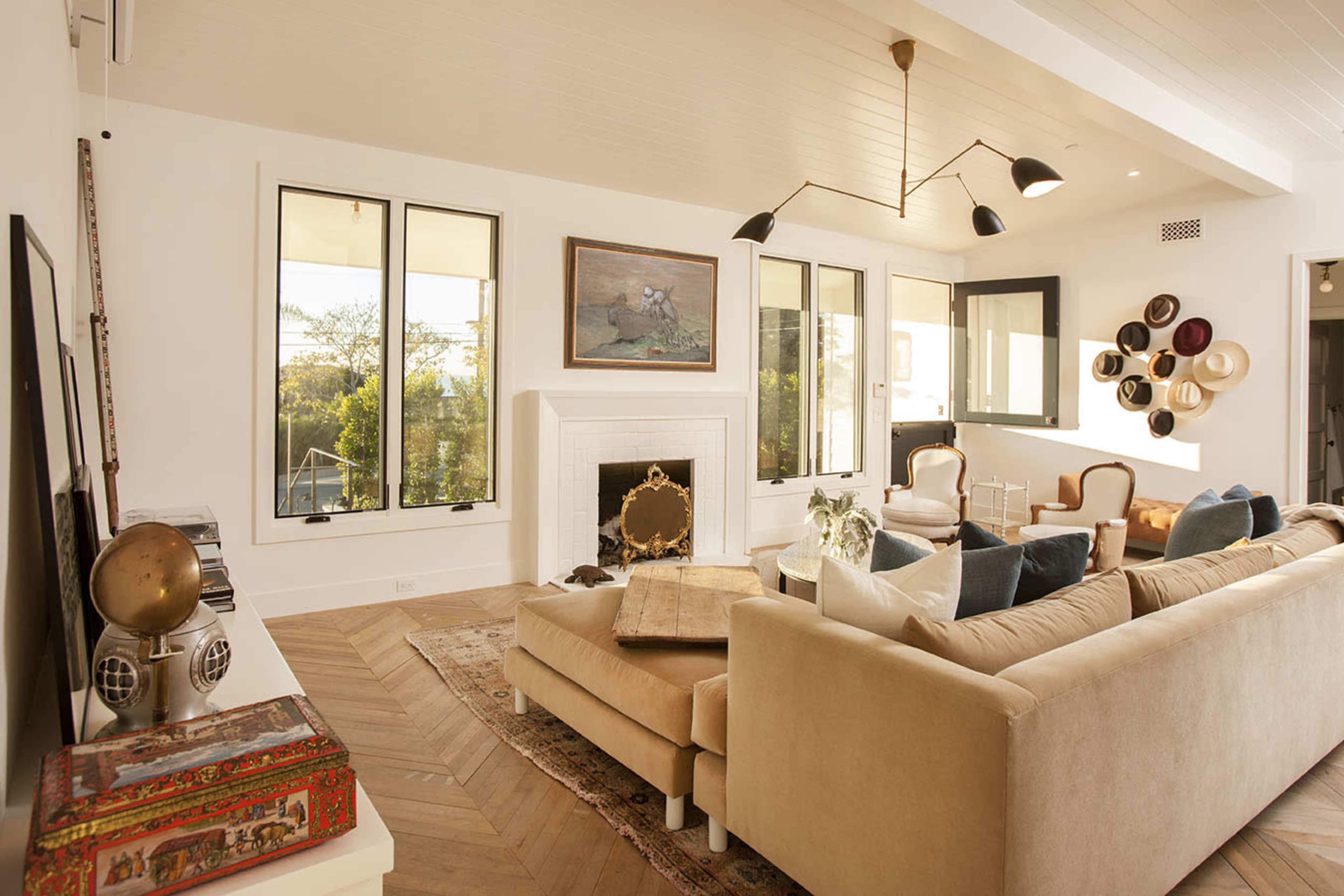A bright living room with large windows, a stylish sofa, and a decorative fireplace.