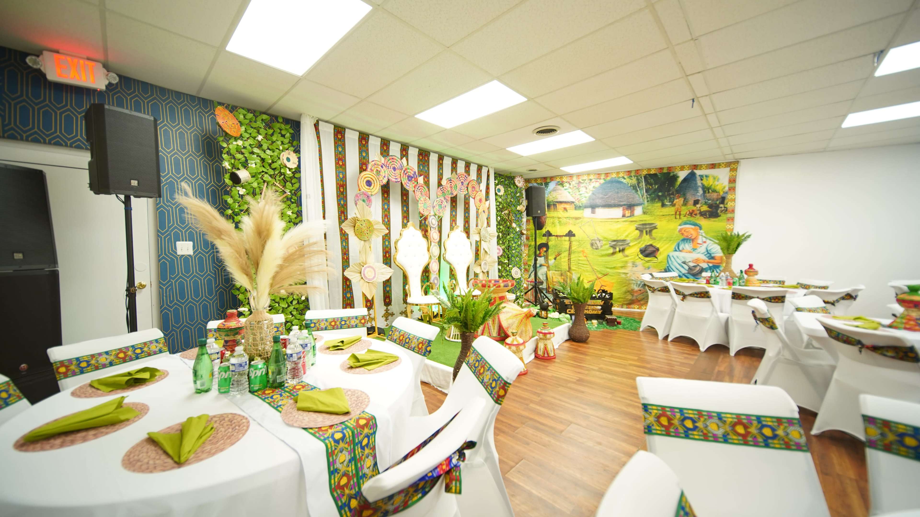 The image shows an elegantly decorated dining area with white tables, colorful table linens, and vibrant wall art featuring a pastoral scene.