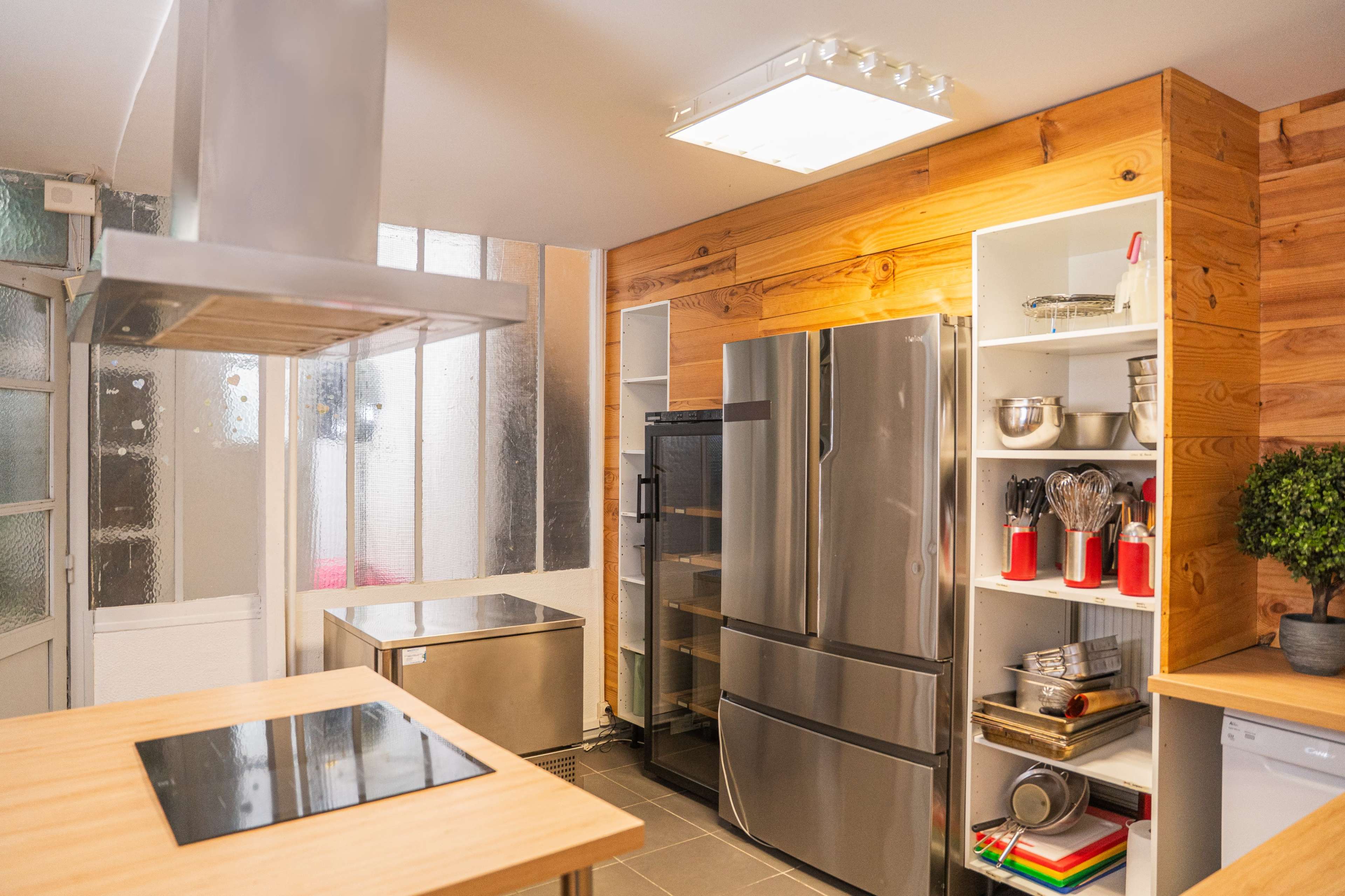 The kitchen features a modern design with stainless steel appliances, wooden accents, and organized shelving.