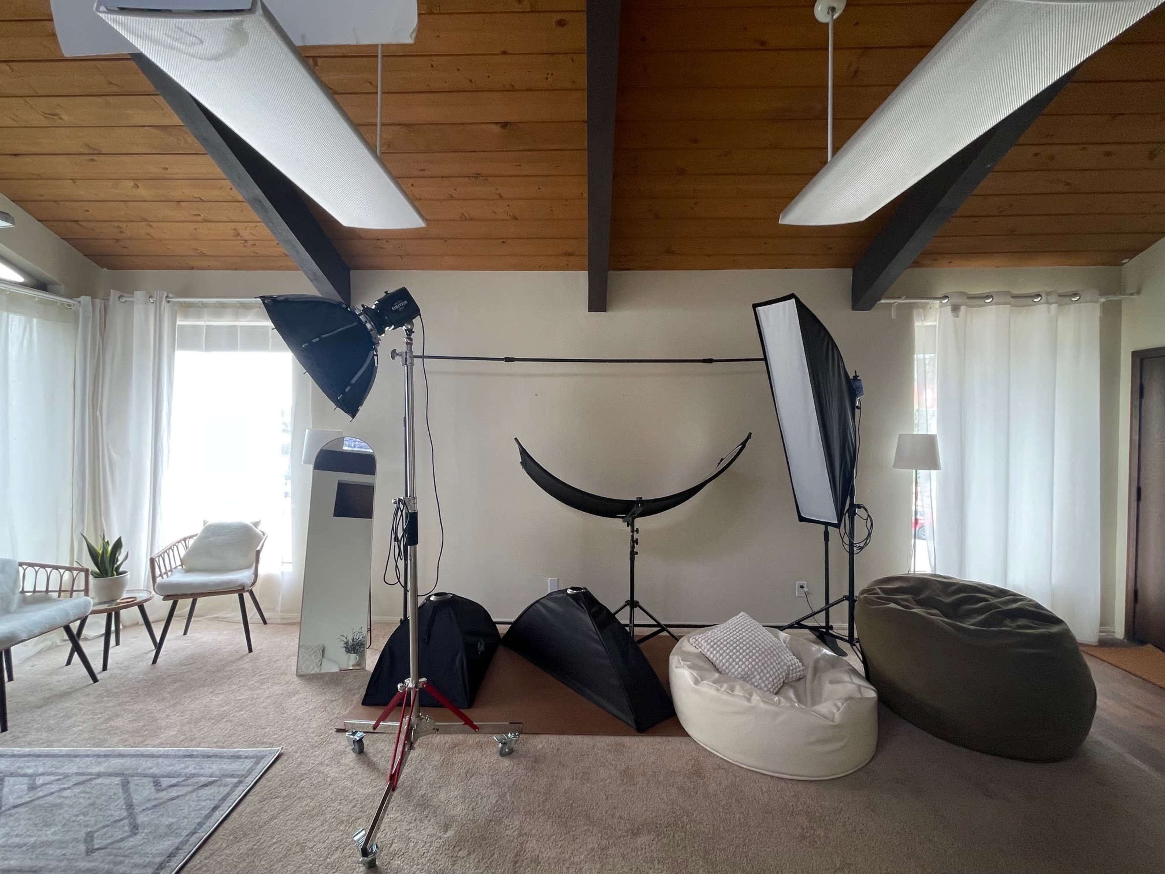 The image shows a well-lit indoor space with photography equipment, including lights, reflectors, and various props, set up on a carpeted floor.