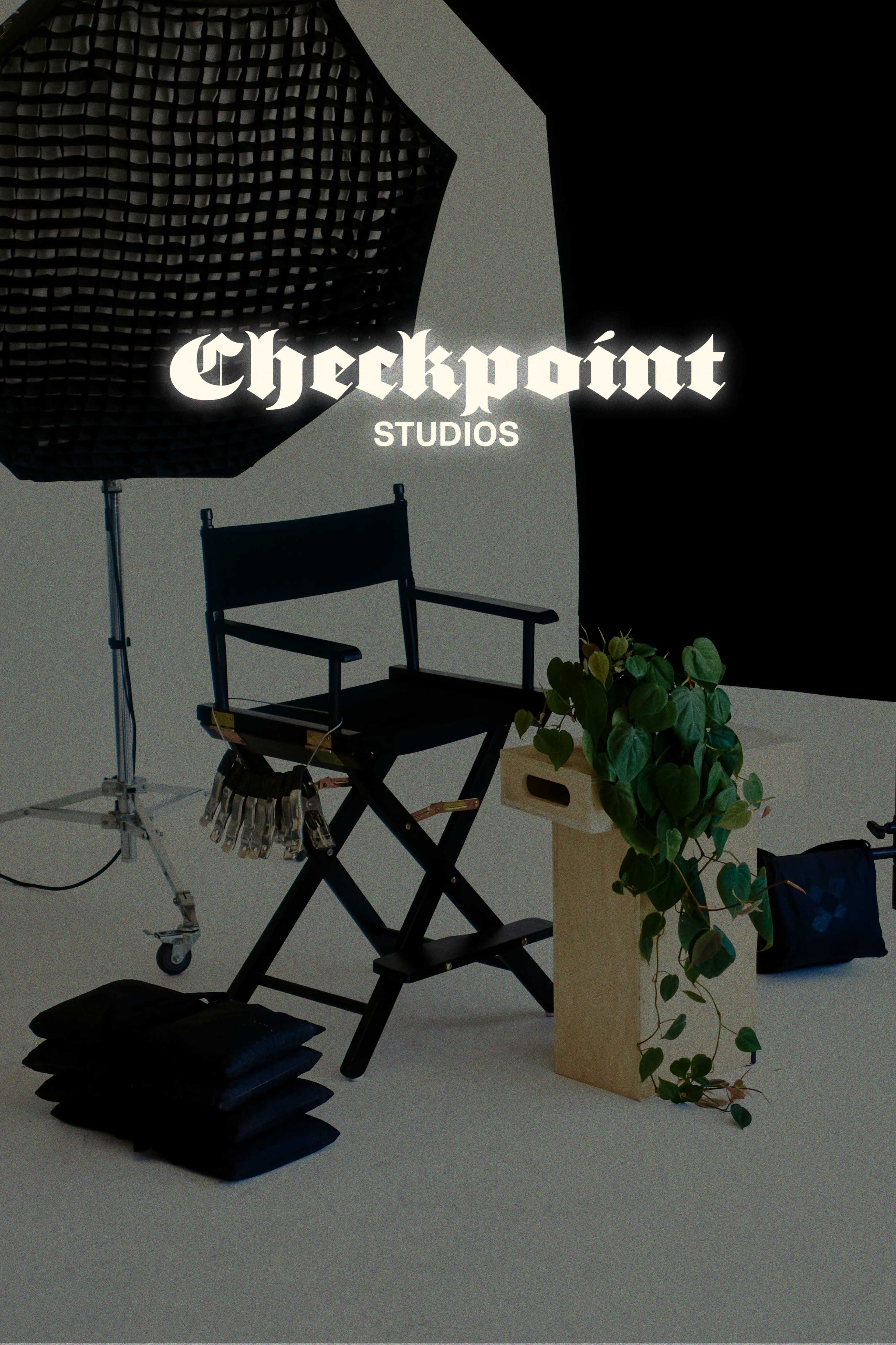 The image features a film set with a director's chair, a plant, and various studio equipment against a dark background.
