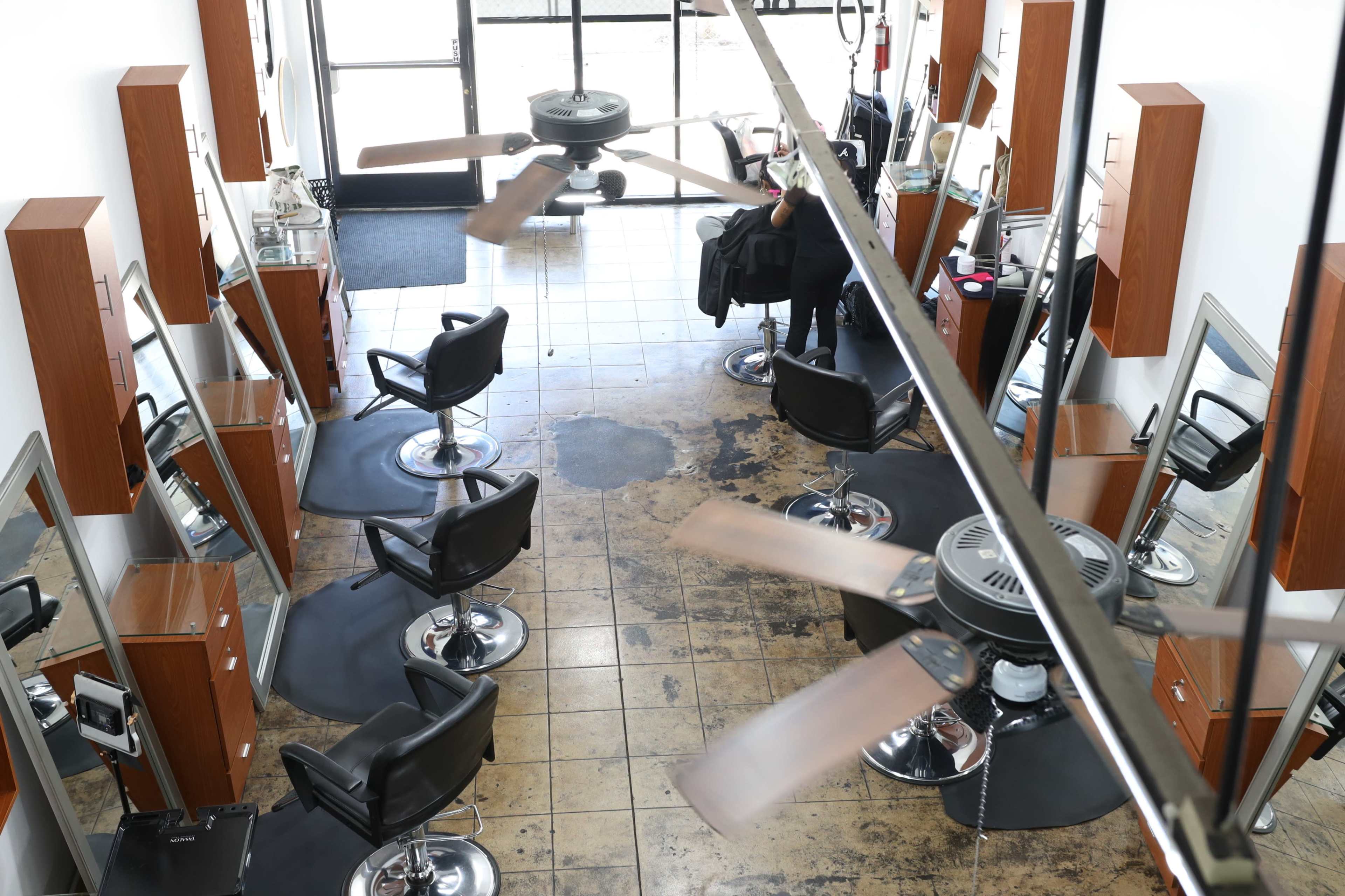 The interior of a hair salon with several styling chairs, mirrors, and ceiling fans.