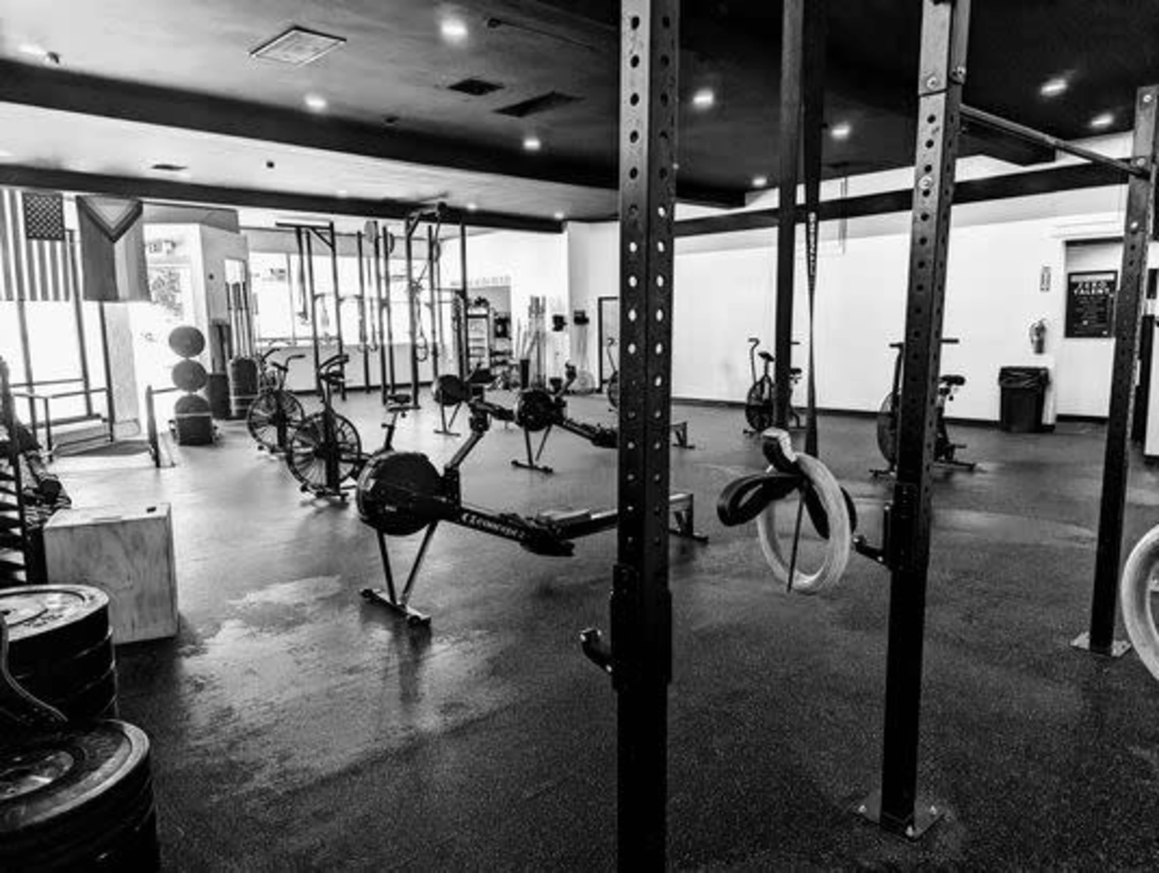 A spacious gym with various exercise equipment, including rowing machines, stationary bikes, and weightlifting racks, all arranged in a well-lit environment.